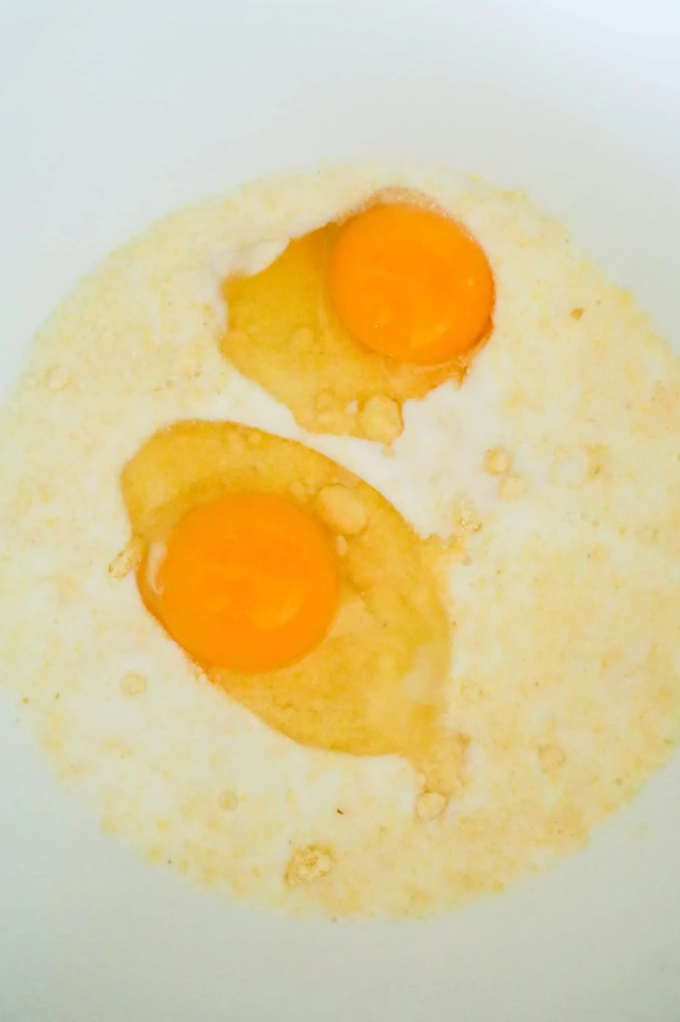 eggs and milk on top of jiffy cornbread mix in a mixing bowl