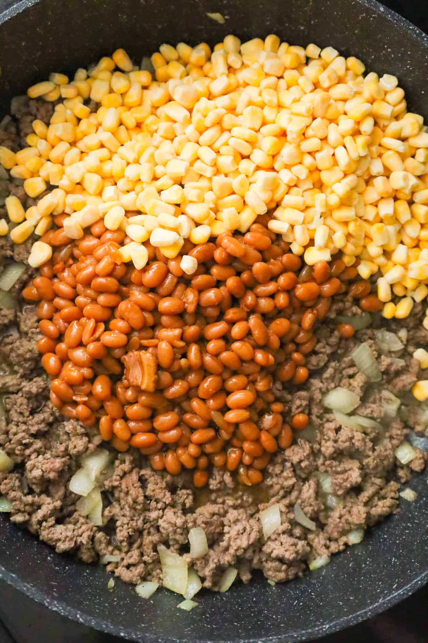 baked beans, frozen corn kernels and cooked ground beef in a skillet