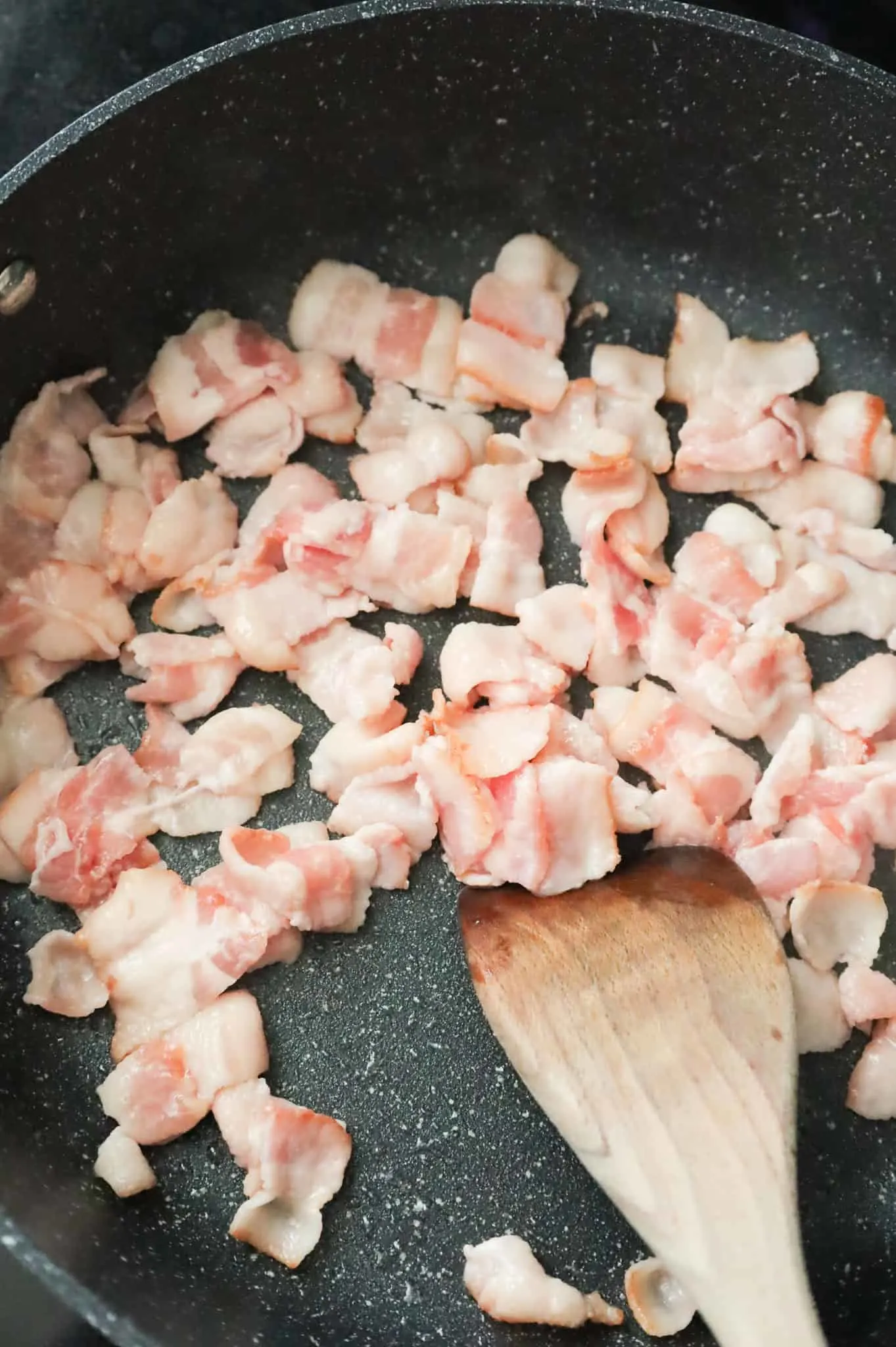 bacon pieces cooking in a skillet