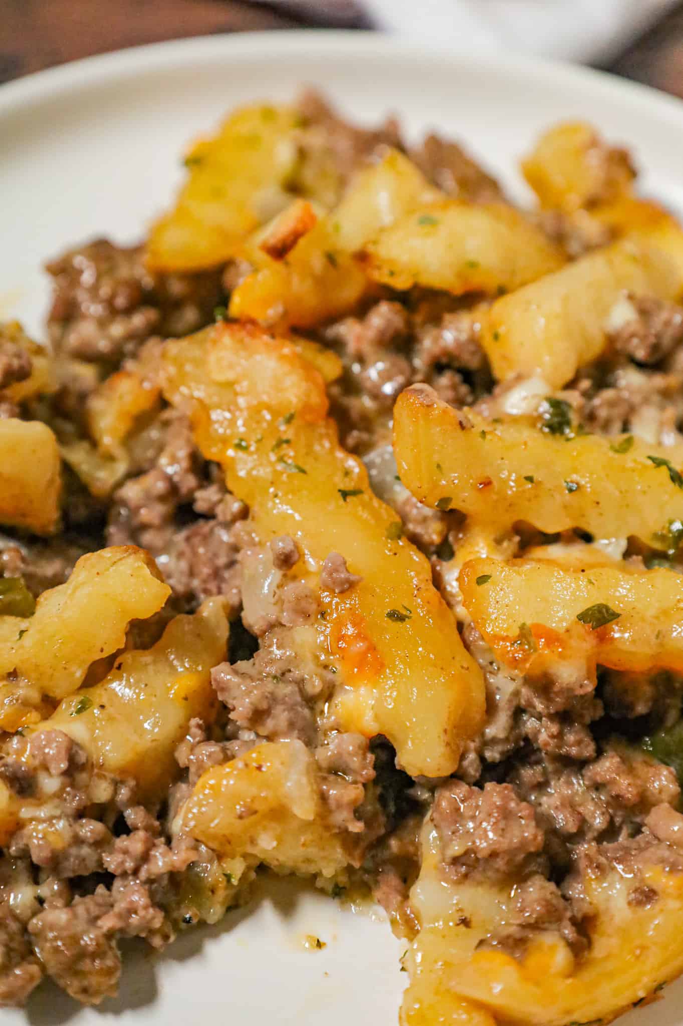 French Fry Casserole is a hearty ground beef casserole made with cream of mushroom soup, cheddar soup, diced onions, green peppers and shredded cheese all topped with crinkle cut fries.