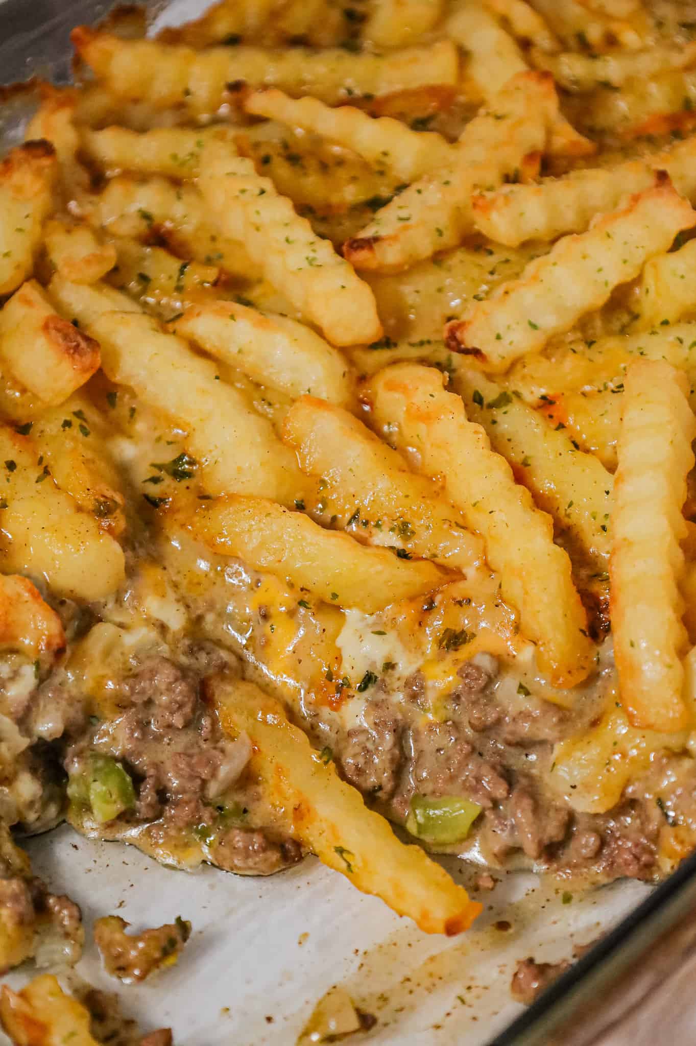 French Fry Casserole is a hearty ground beef casserole made with cream of mushroom soup, cheddar soup, diced onions, green peppers and shredded cheese all topped with crinkle cut fries.