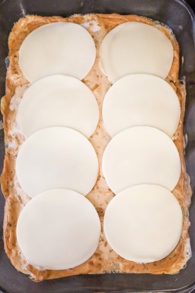 provolone cheese slices on top of pork chops in a baking dish