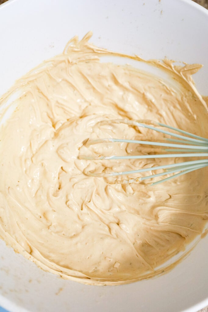 sour cream and spice mixture being whisked in a mixing bowl