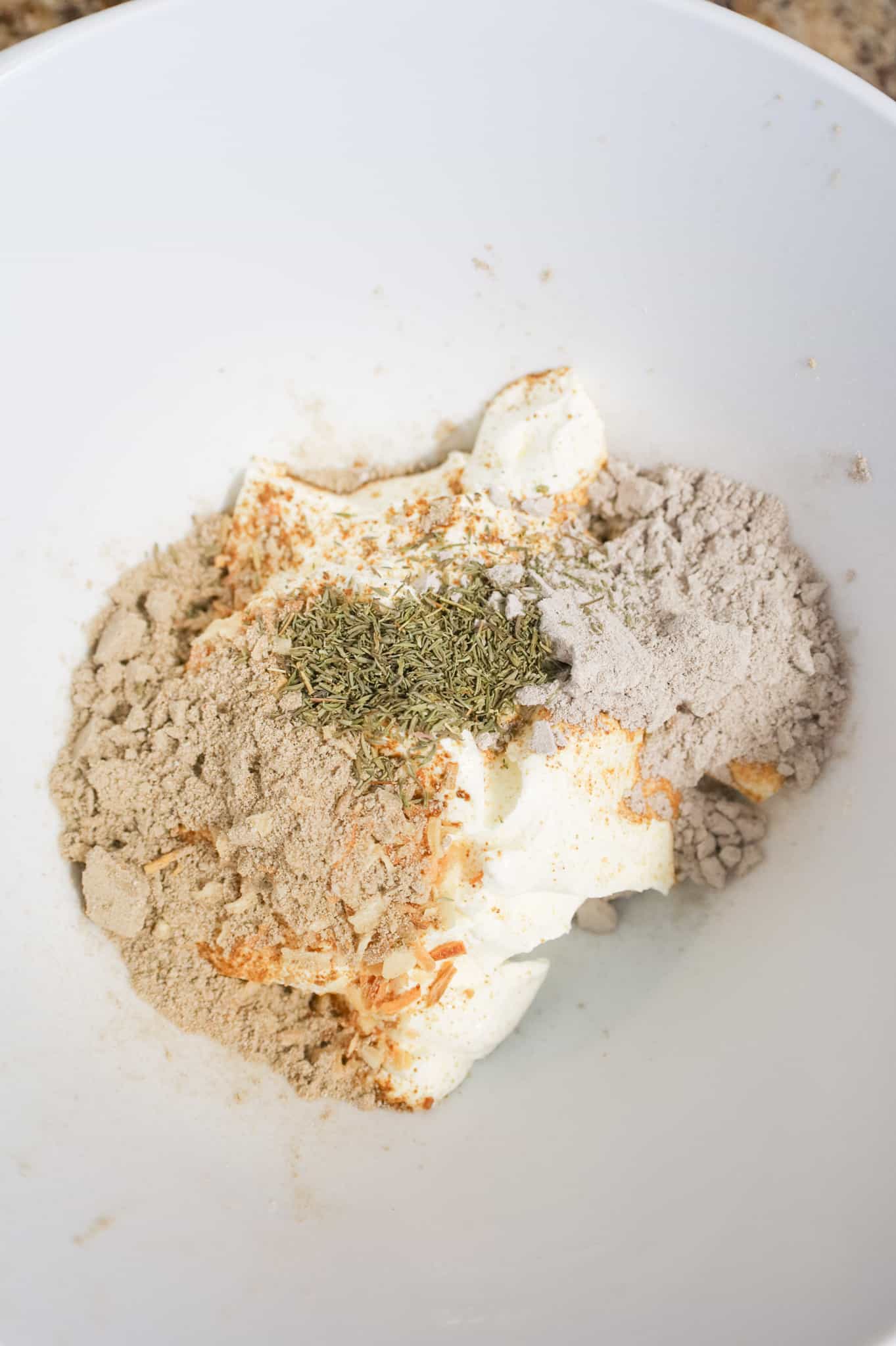 onion soup mix, gravy mix and thyme leaves on top of sour cream in a mixing bowl