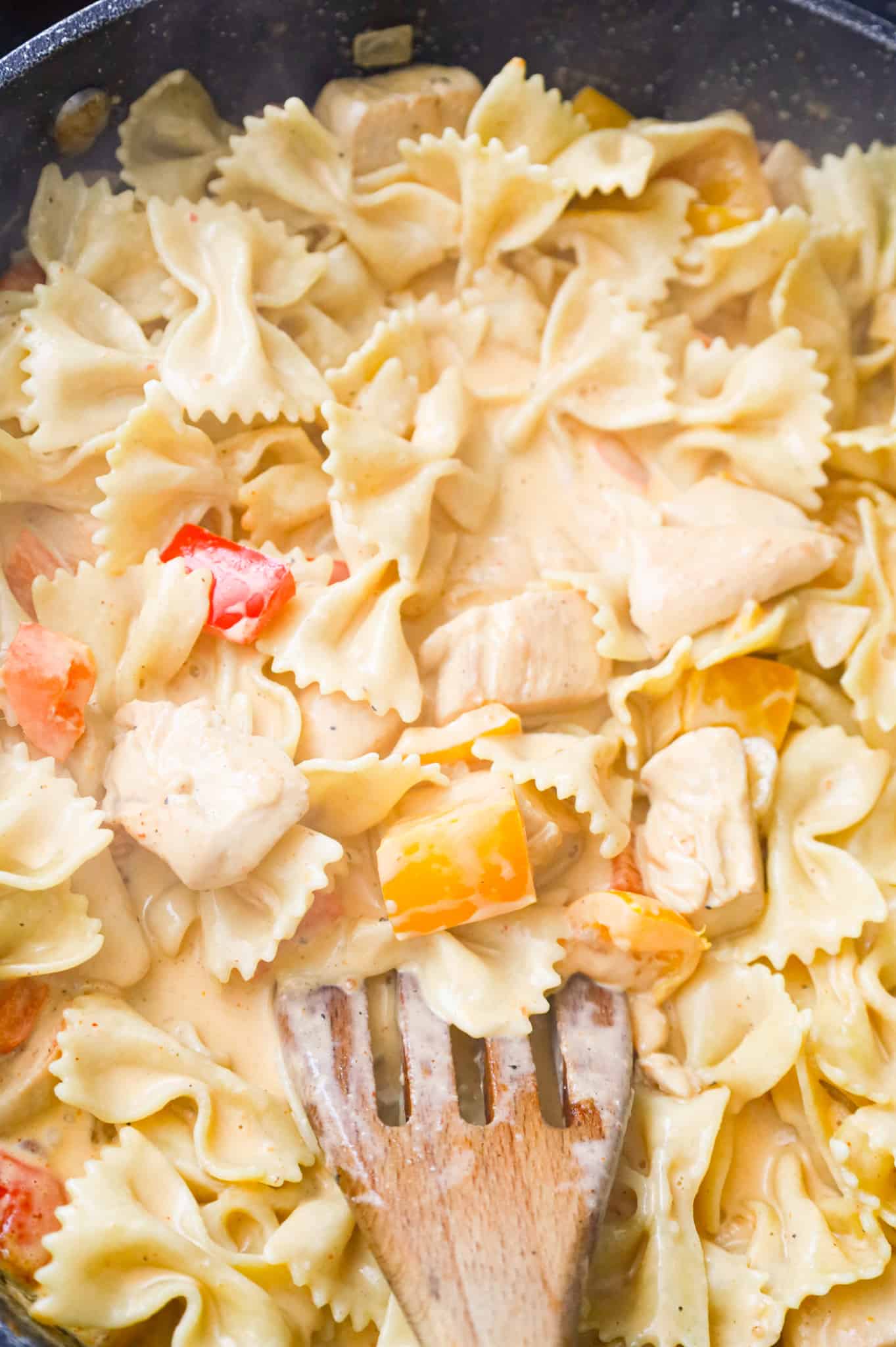 bowtie pasta being stirred into creamy chipotle sauce in a skillet