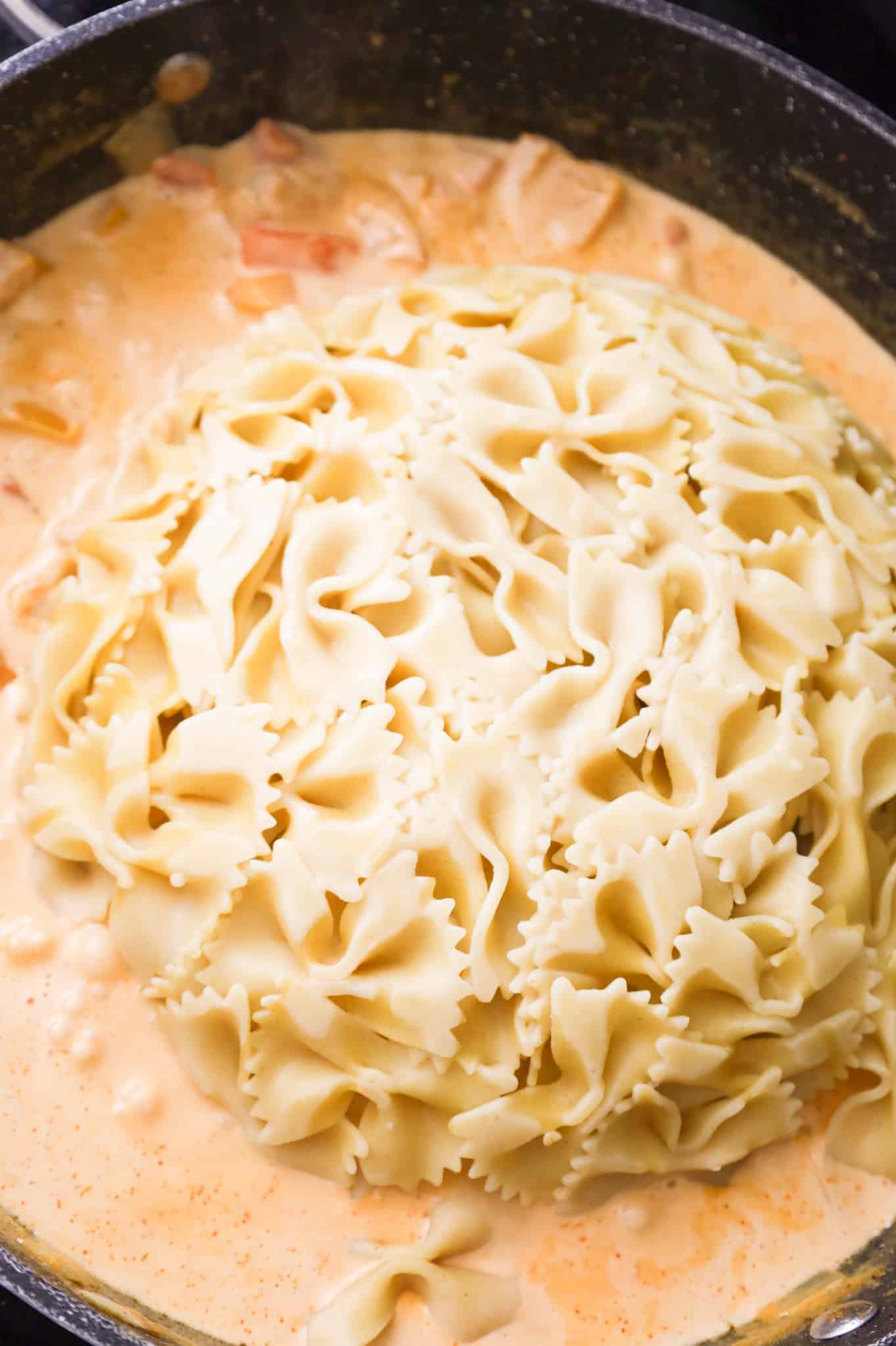 cooked bowtie noodles added to skillet with creamy chipotle sauce
