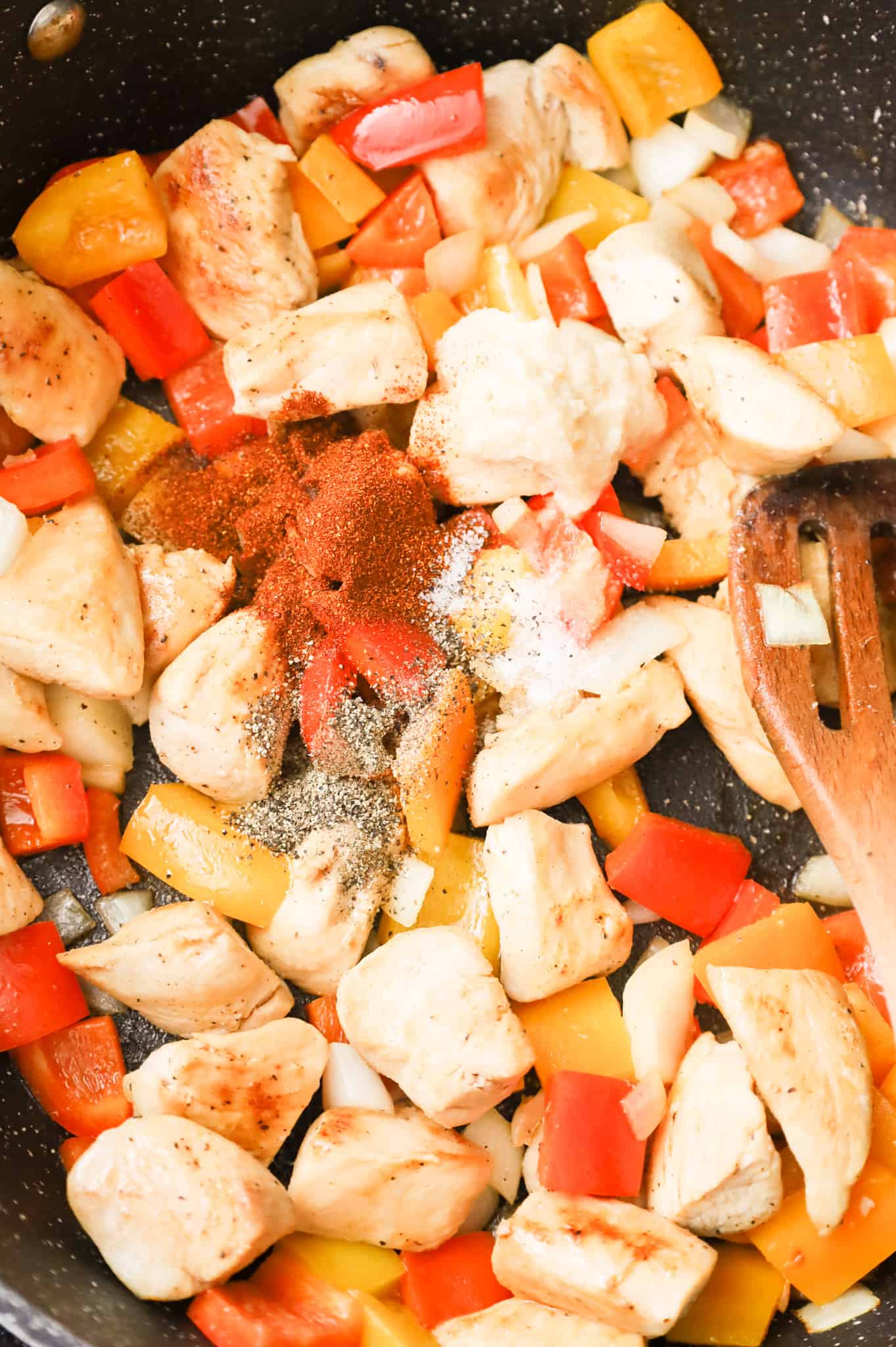 garlic puree, paprika, salt and pepper added to diced peppers and chicken breast chunks in a skillet