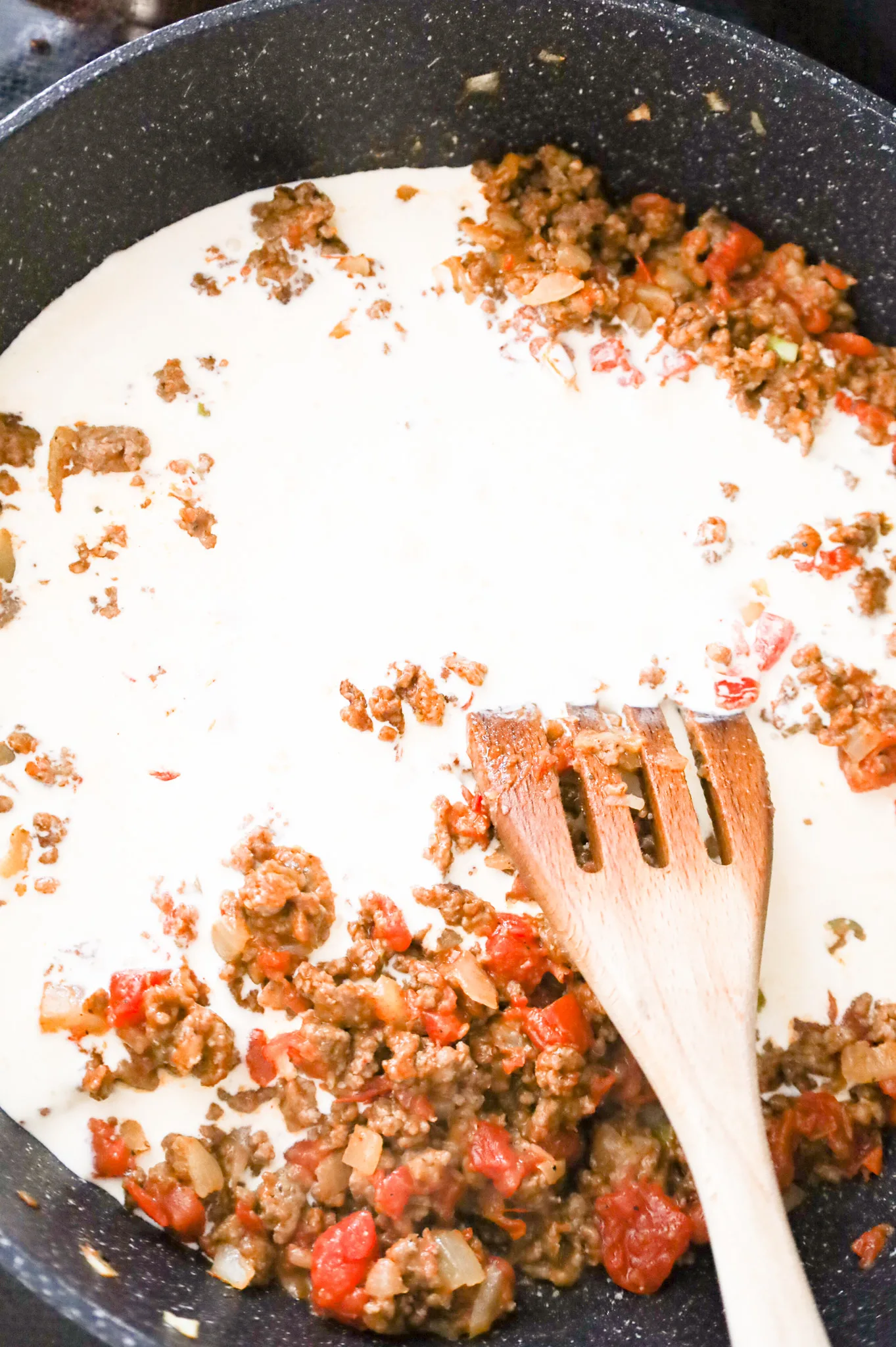 heavy cream added to a skillet with cooked ground beef and Rotel