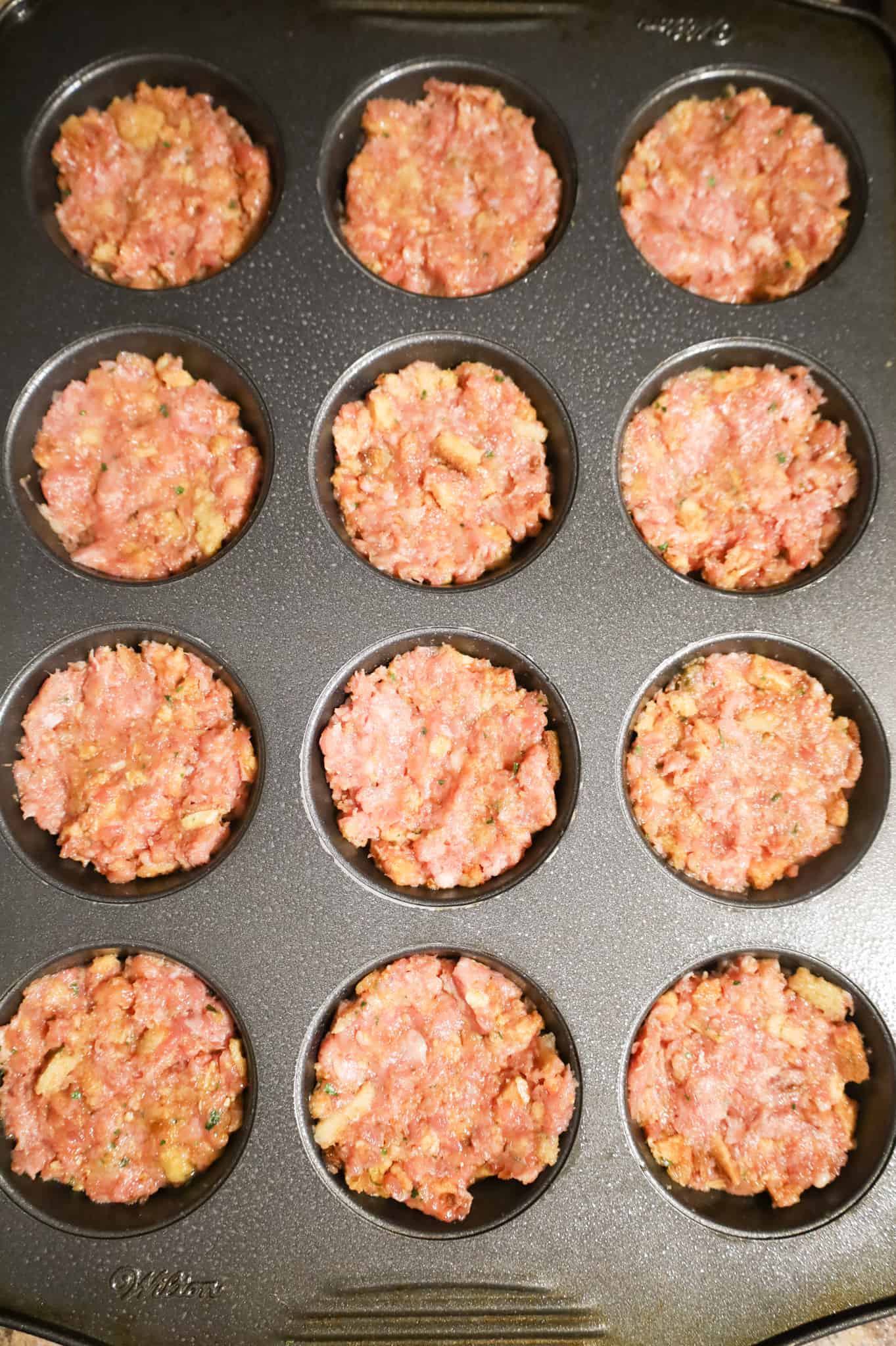 ground turkey meatloaf mixture in a muffin tin before baking
