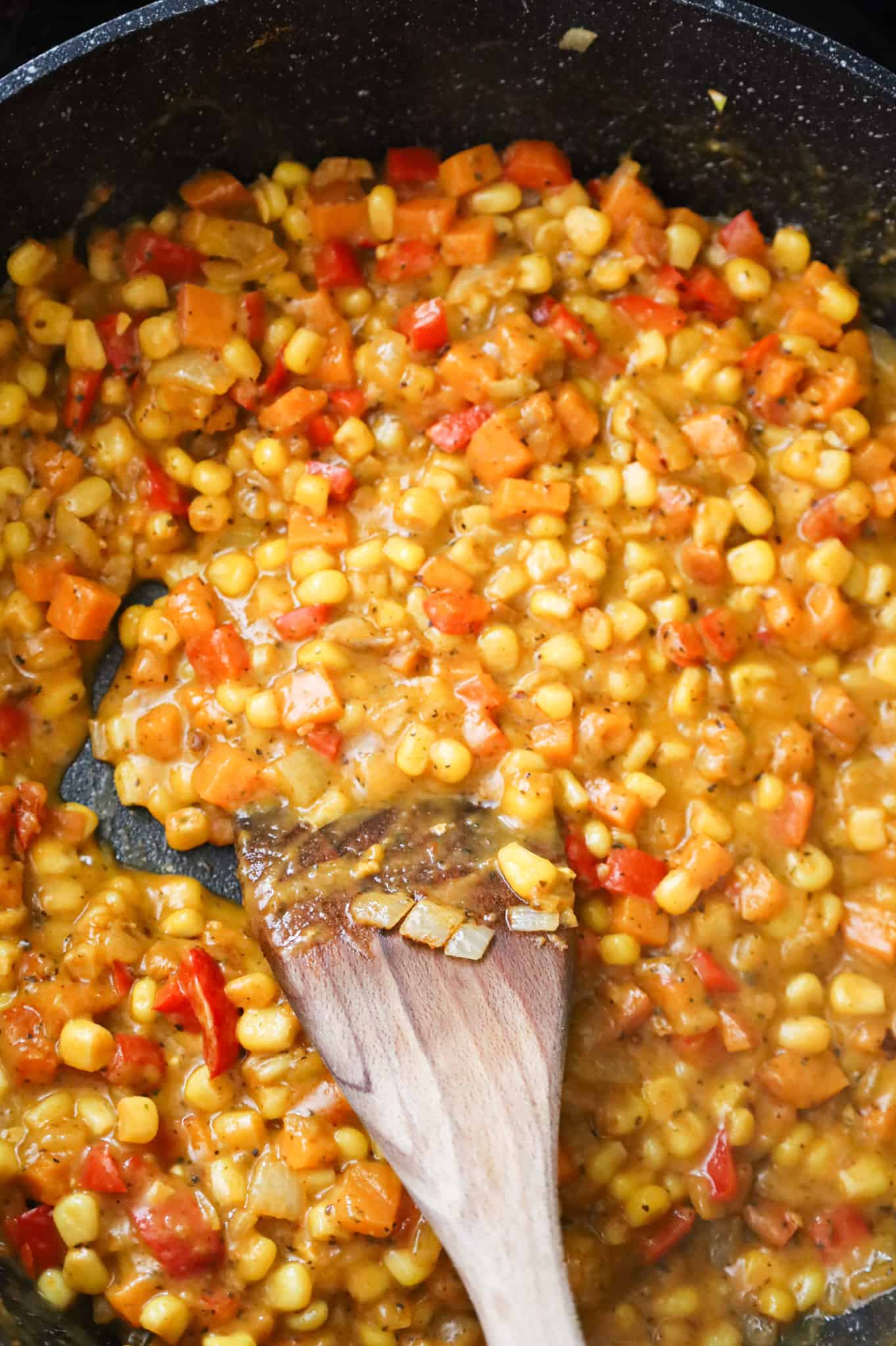 chicken broth and flour mixture thickening in a skillet with diced peppers, sweet potatoes and corn