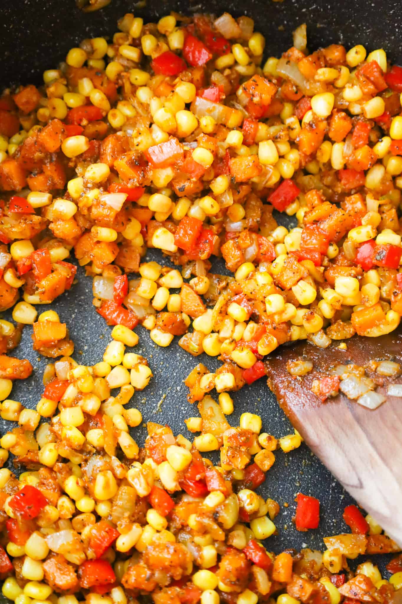 diced peppers, sweet potato and corn cooking in a skillet