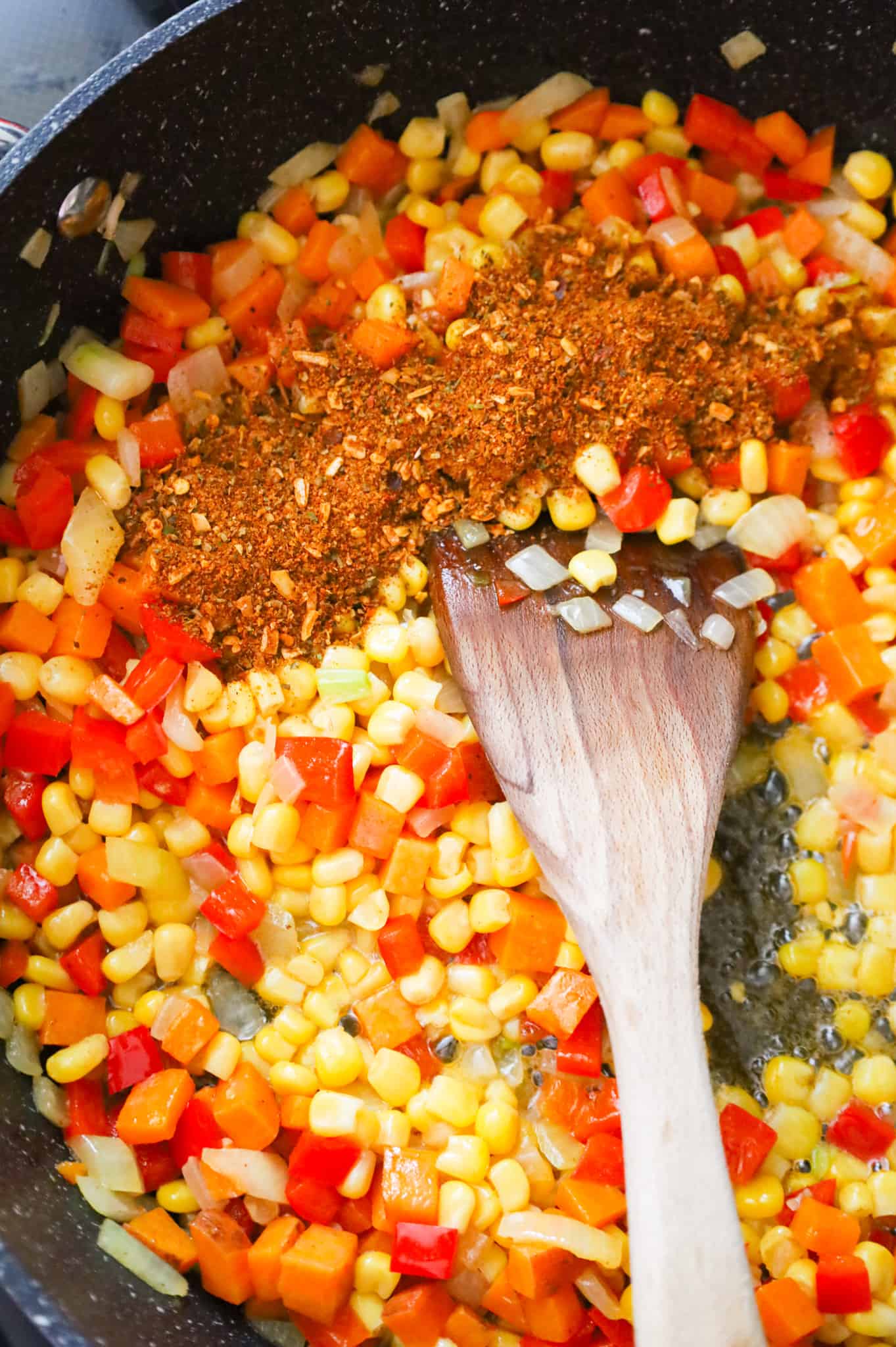 Cajun seasoning added to skillet with corn, diced peppers, diced onions and sweet potatoes