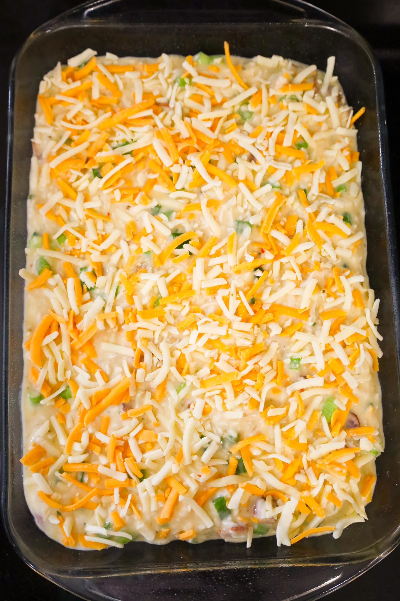 shredded cheese on top of chicken bacon ranch rice mixture in a baking dish