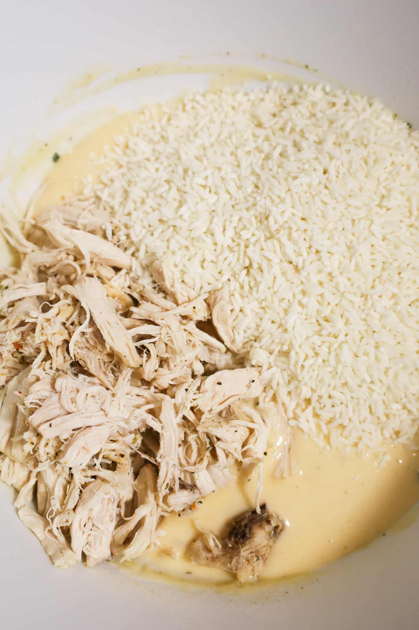 shredded chicken and instant rice on top of cream soup mixture in a mixing bowl