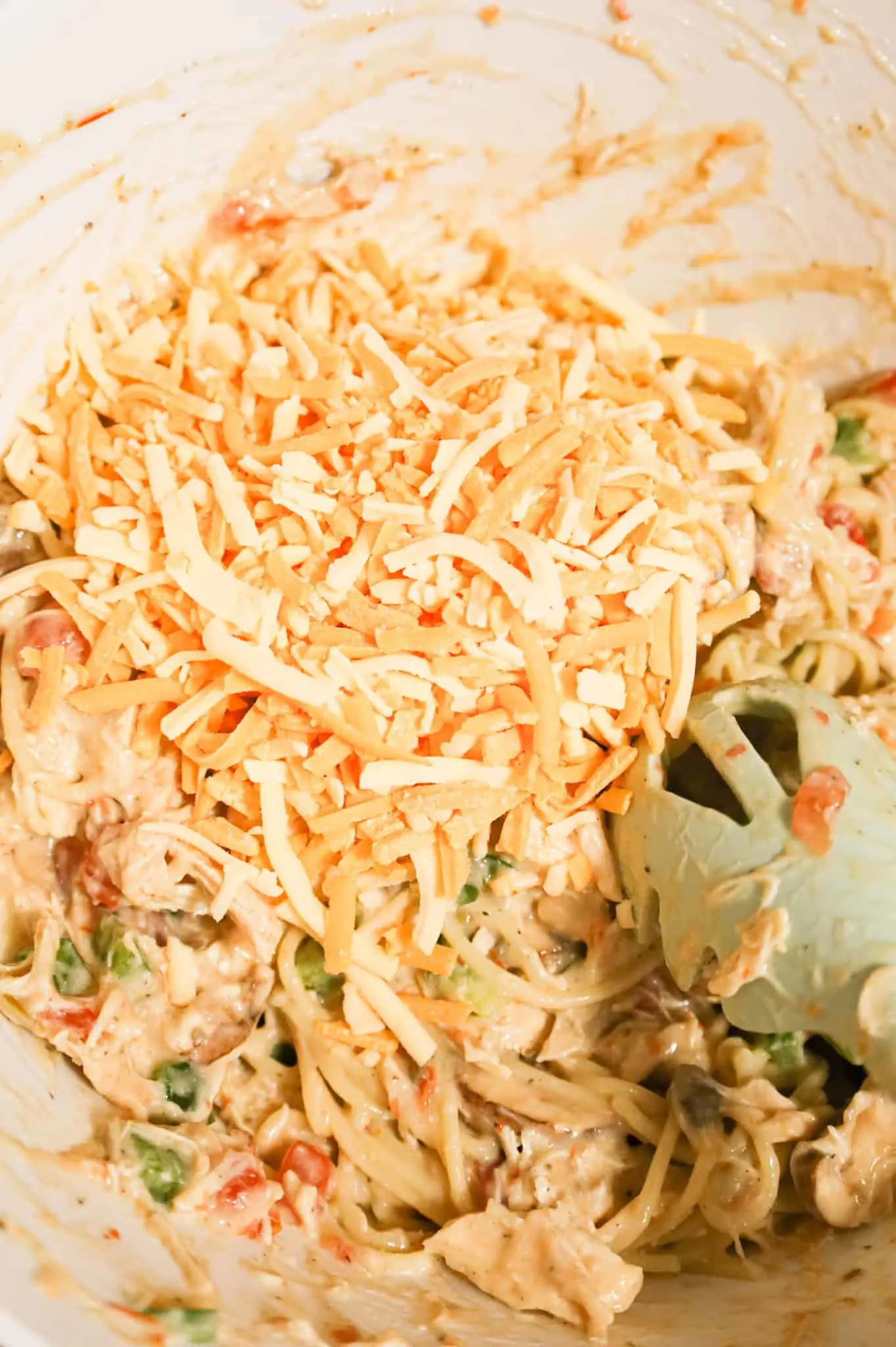 shredded cheese added to mixing bowl with creamy chicken spaghetti mixture