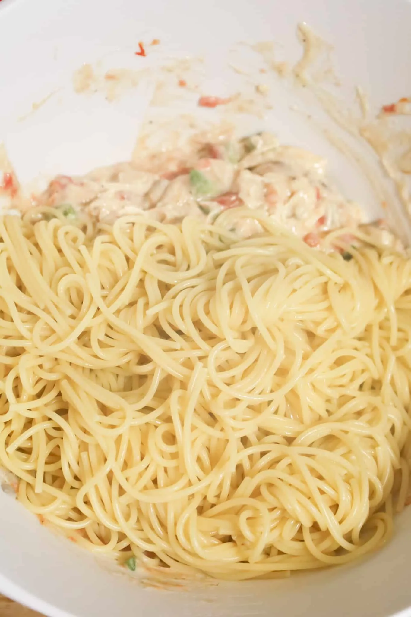 cooked spaghetti noodles added to mixing bowl with creamy chicken mixture