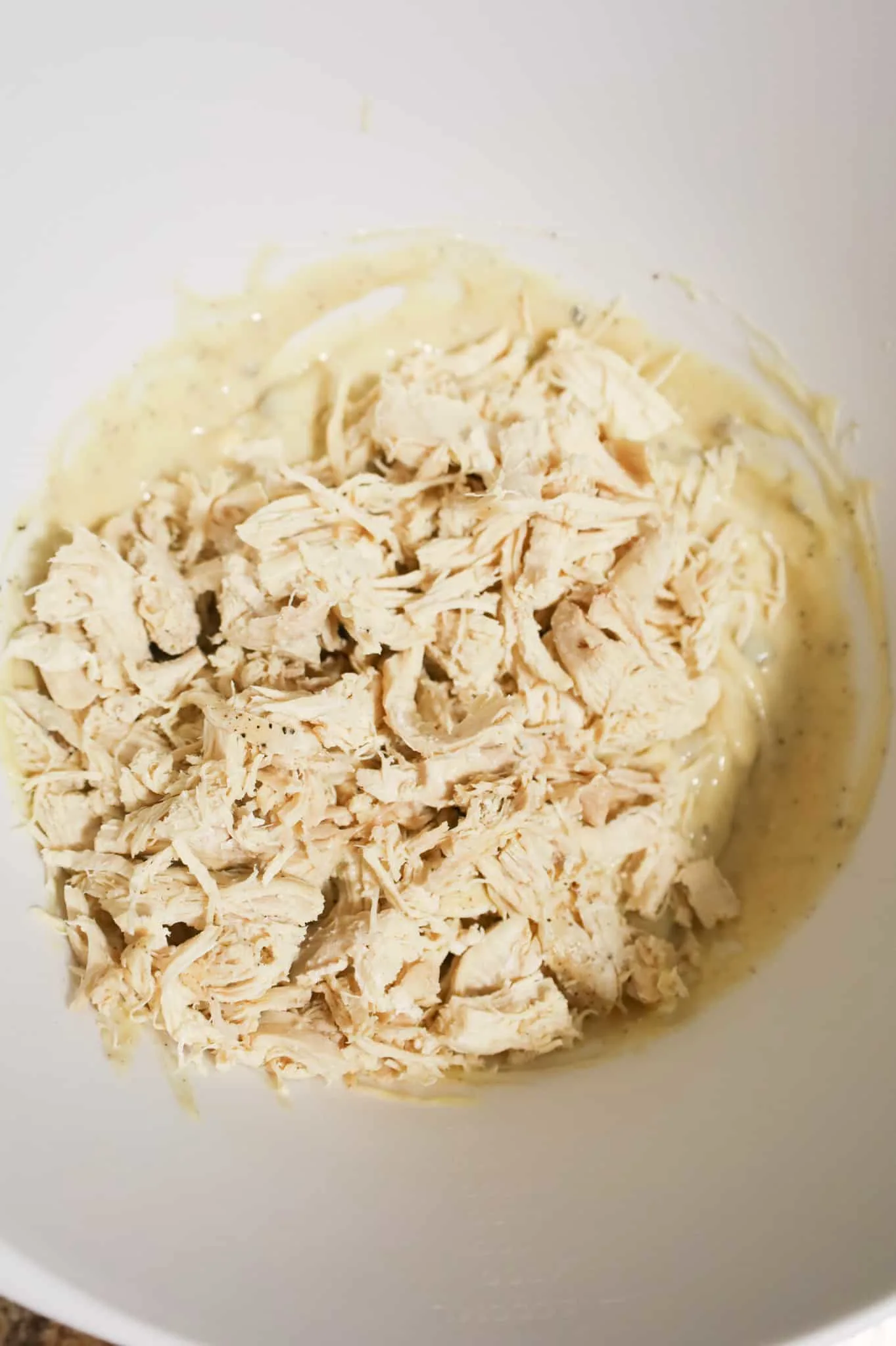 shredded chicken on top of cream soup mixture in a mixing bowl
