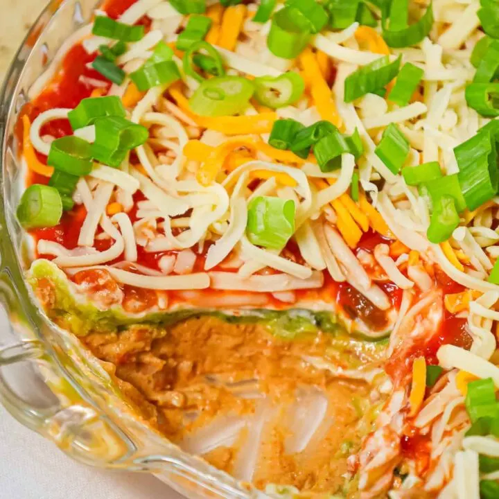  5 Layer Dip is a delicious cold dip recipe made with refried beans, cream cheese, taco seasoning, guacamole, sour cream, salsa, shredded cheese and chopped green onions.