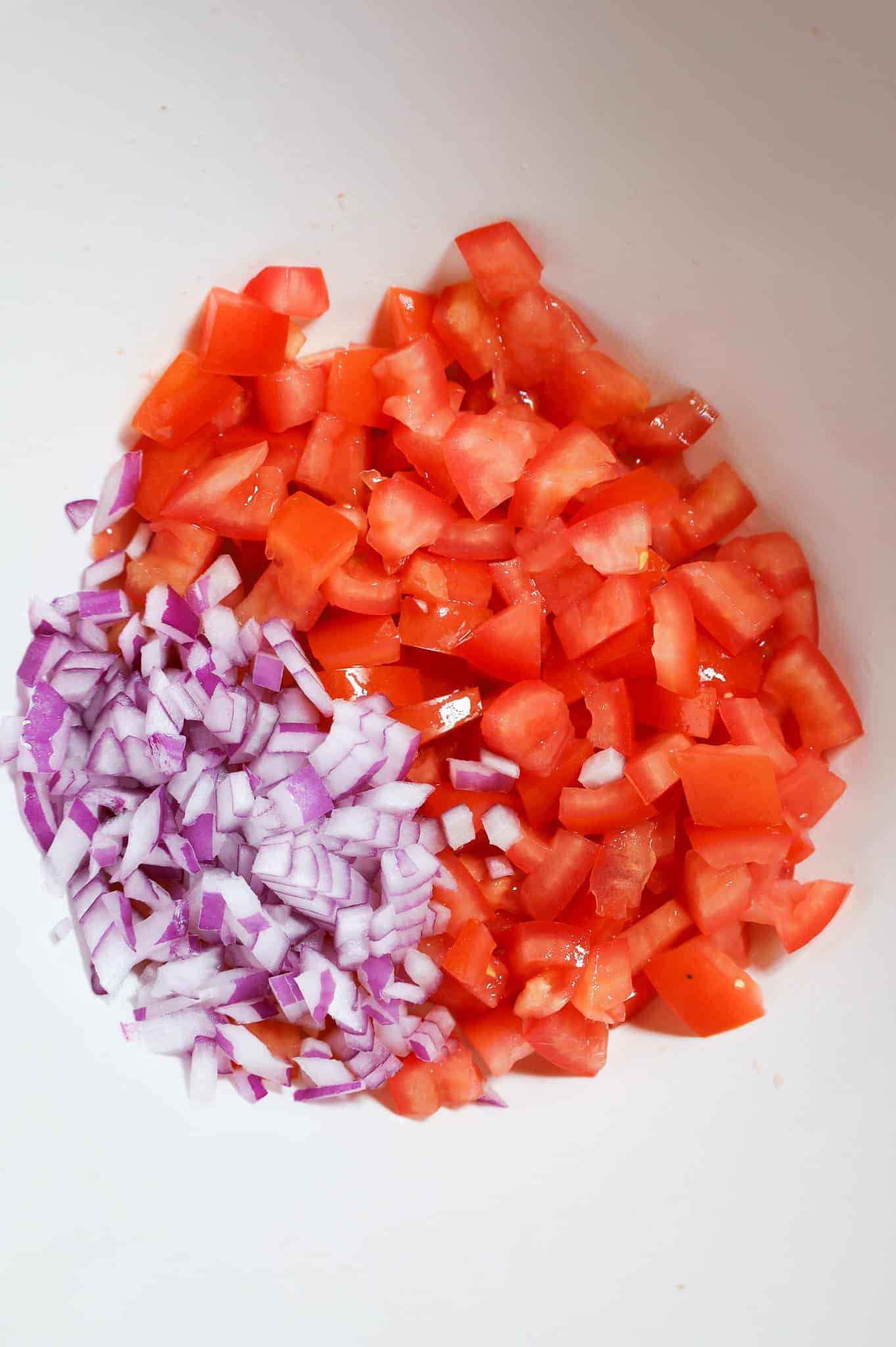 diced red onions and diced tomatoes in a mixing bowl