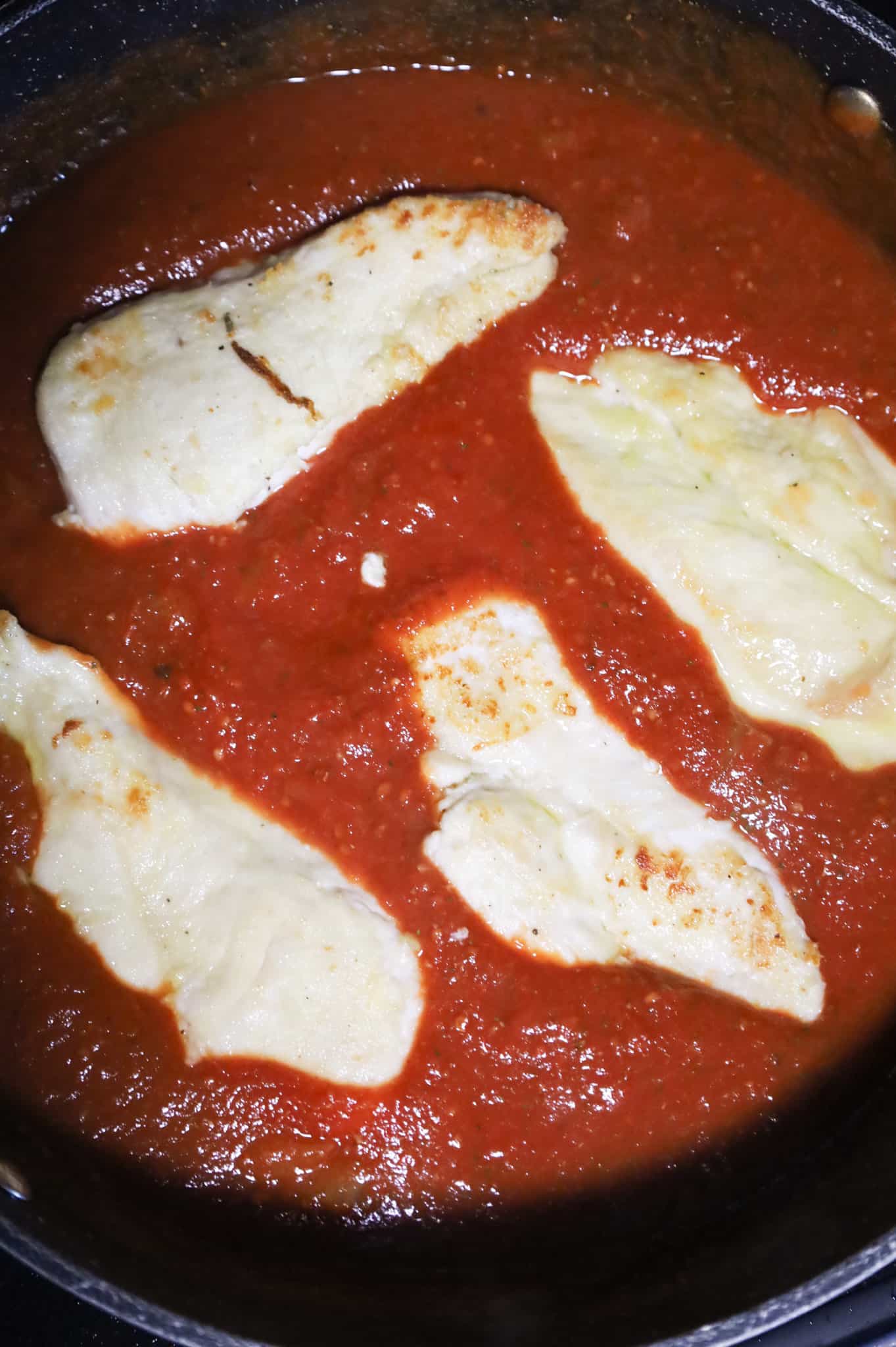 chicken cutlets in a skillet with tomato sauce
