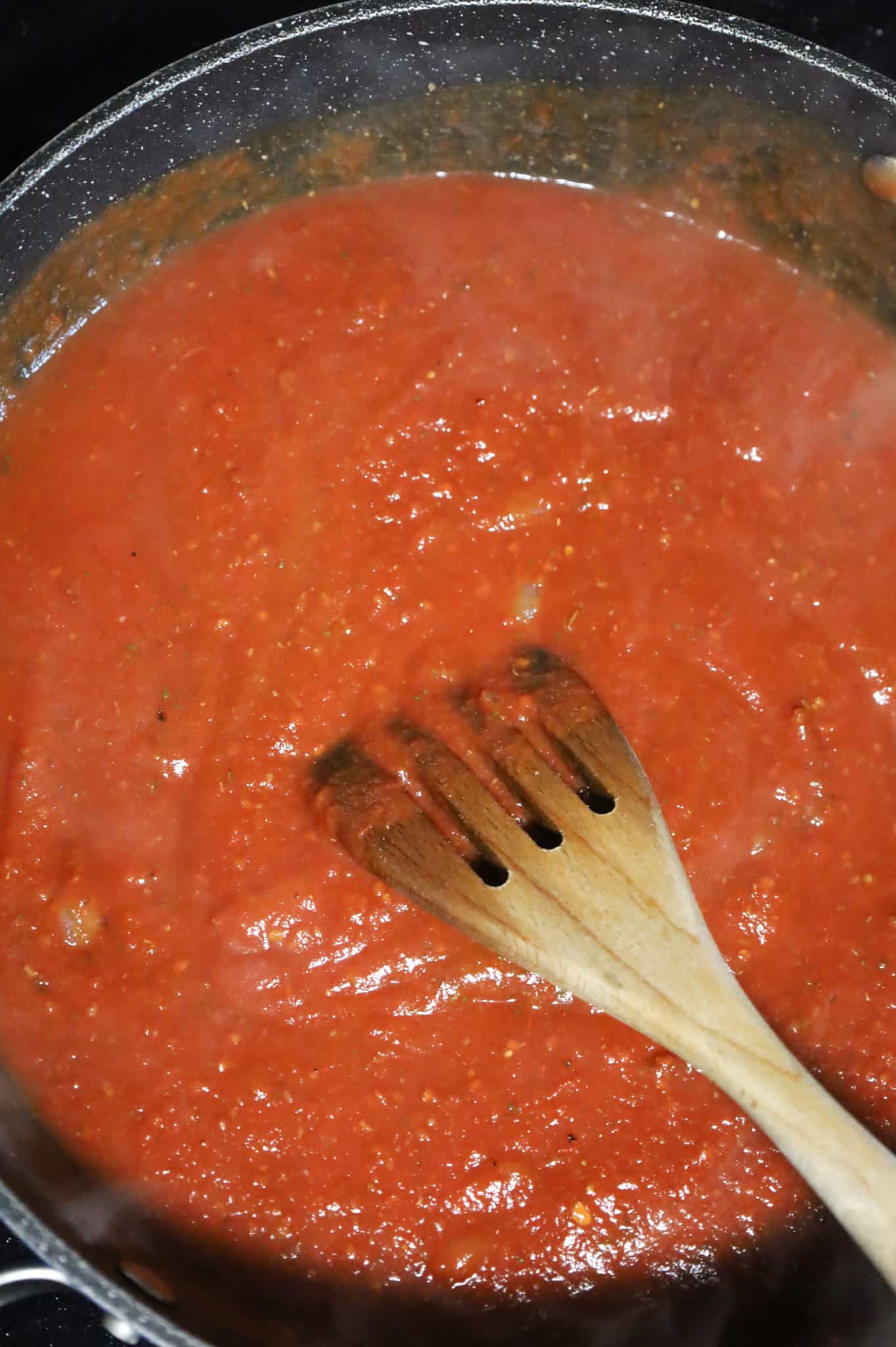 stirring tomato marsala sauce in a skillet