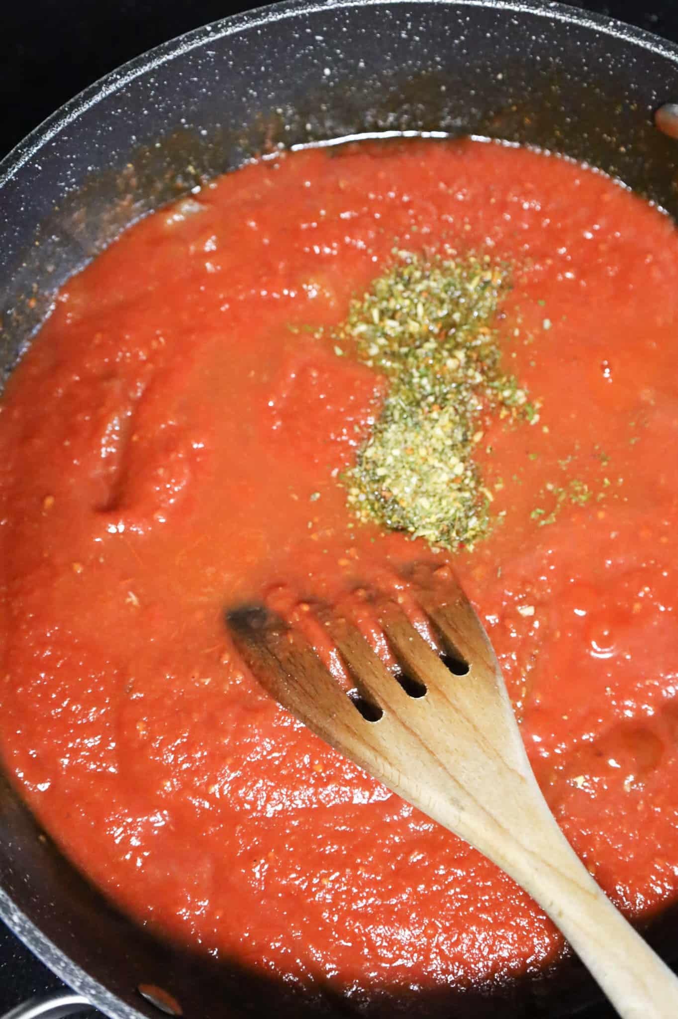 Italian seasoning and water added to skillet with crushed tomatoes