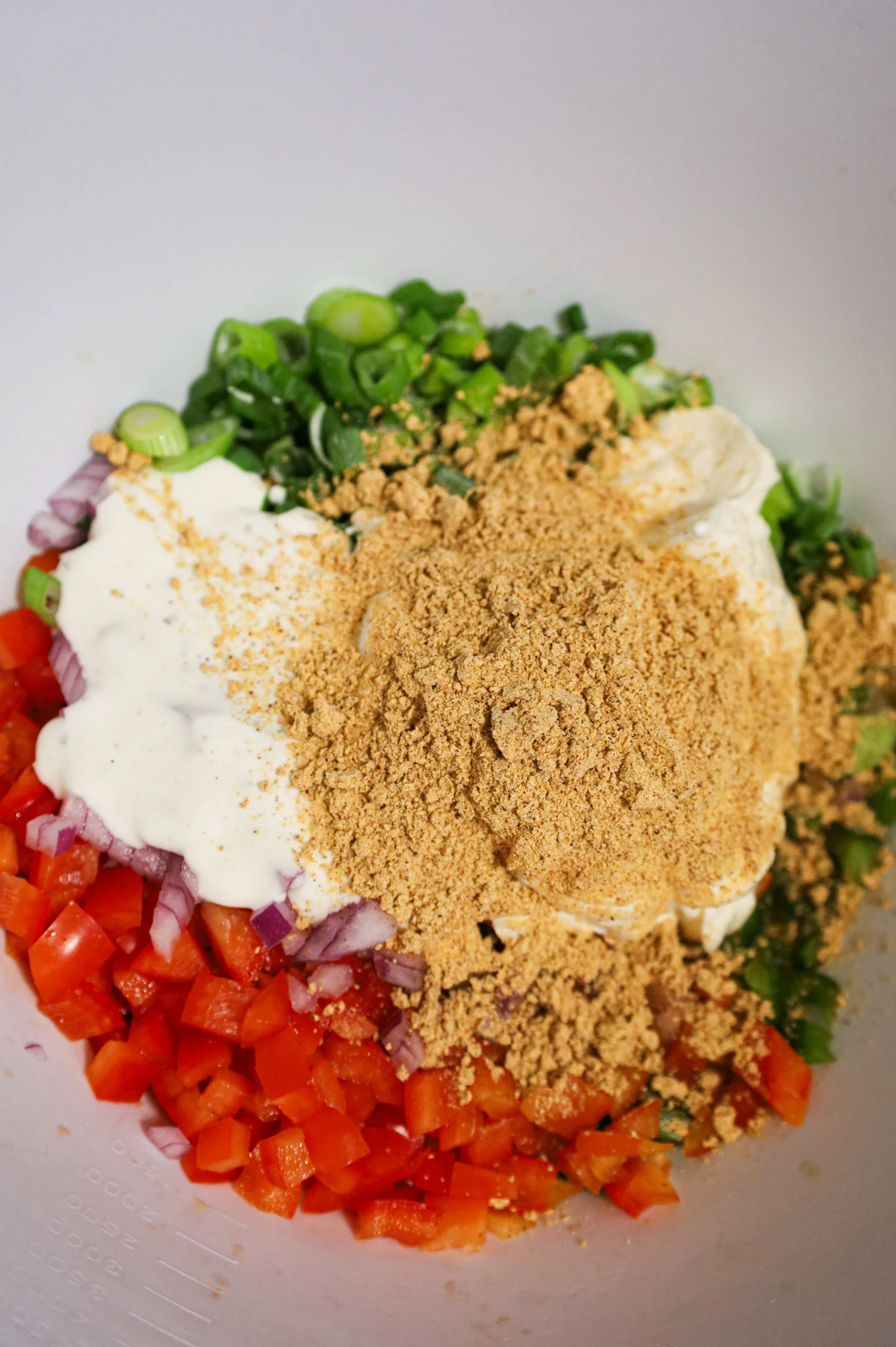taco seasoning, mayo and ranch dressing on top of diced veggies in a mixing bowl