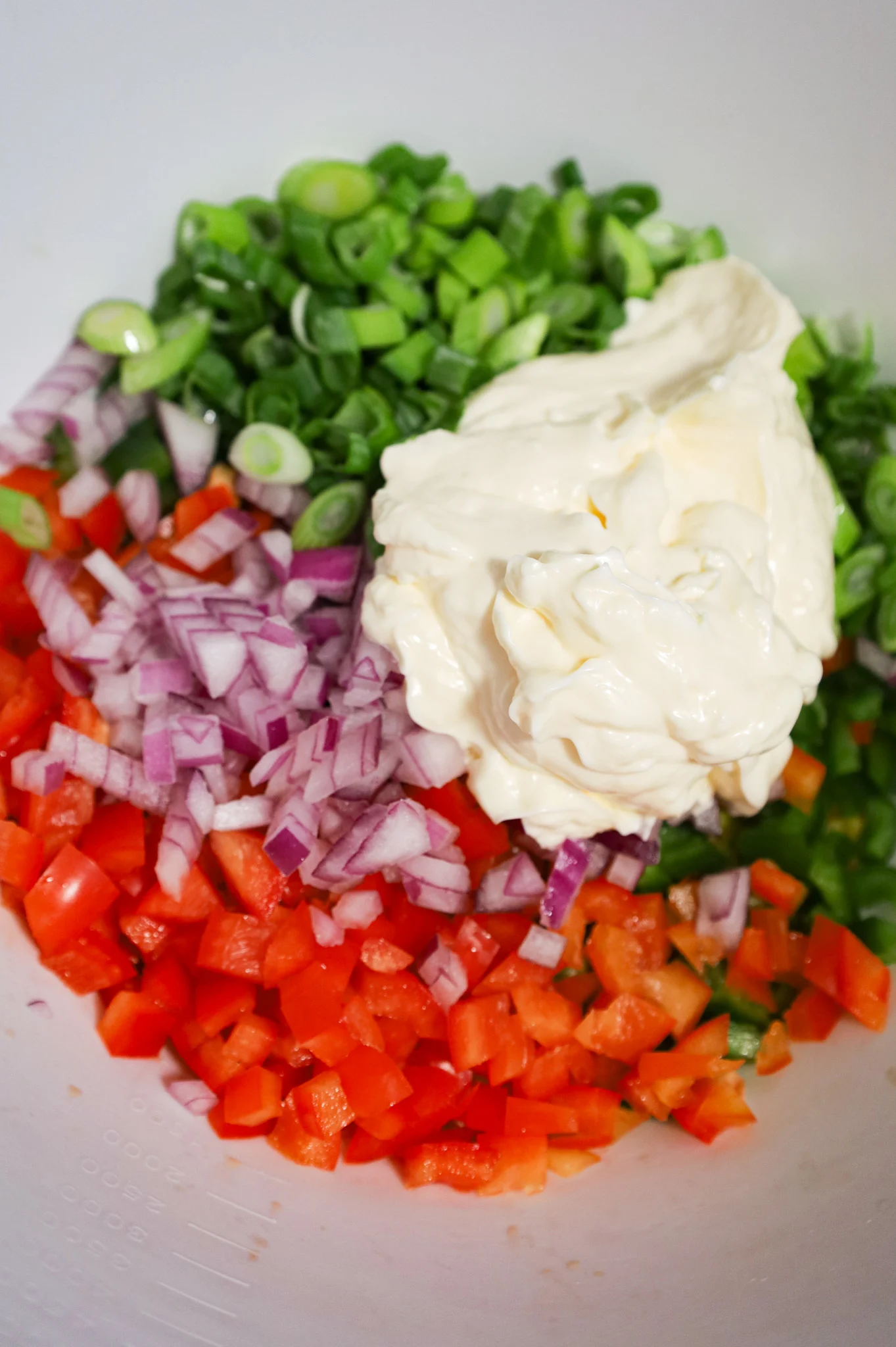 mayo on top of diced veggies in a mixing bowl