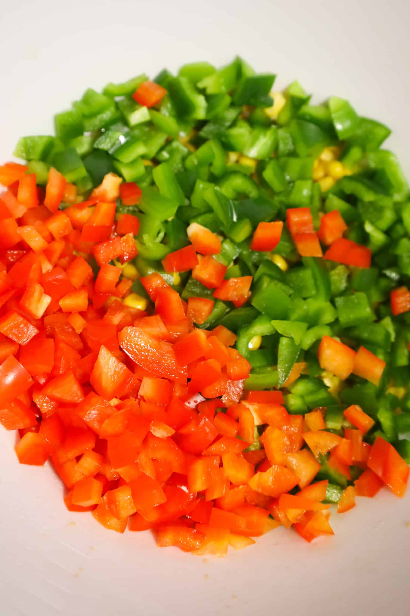 diced red and green bell peppers in a mixing bowl