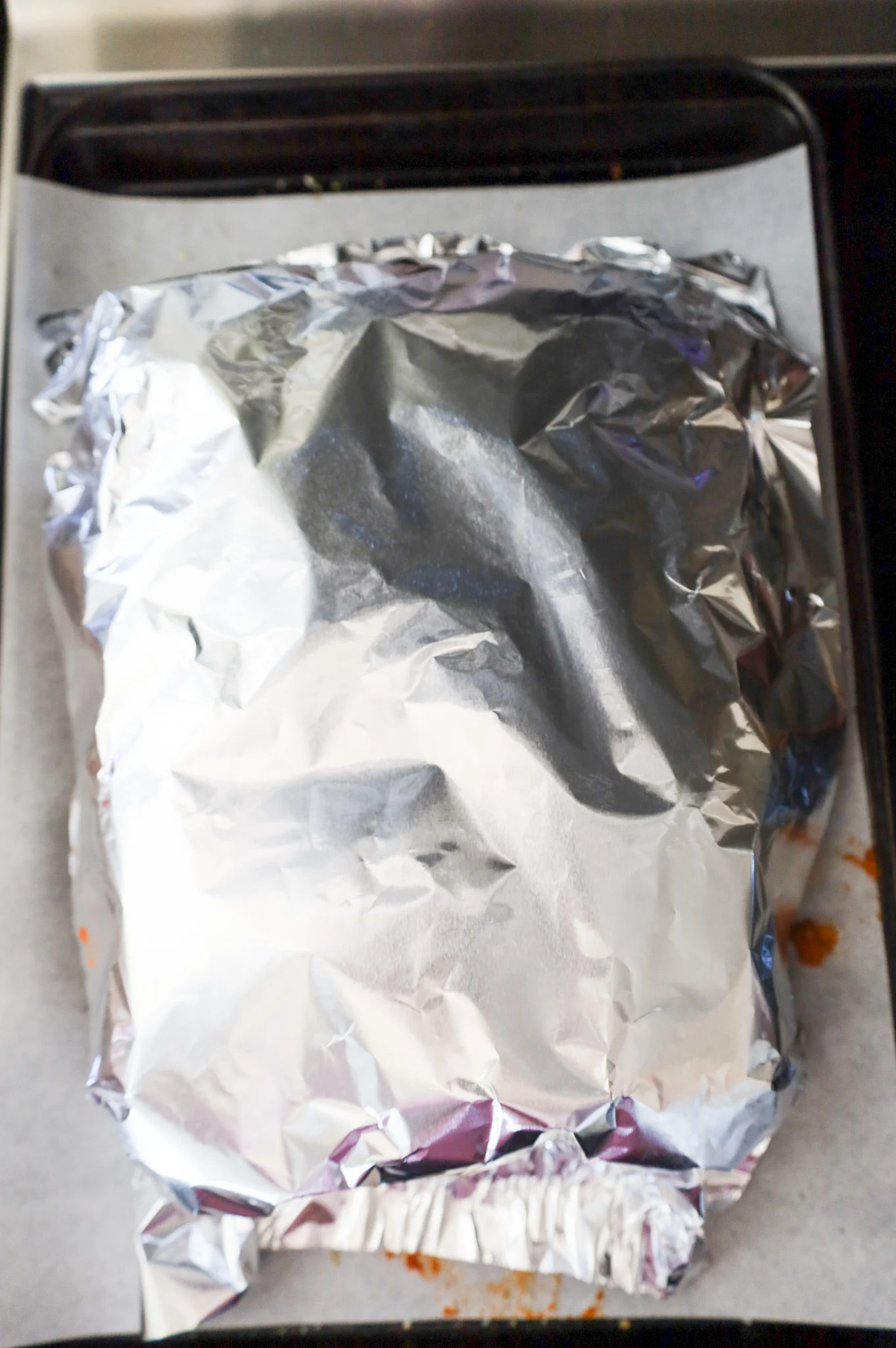 aluminum foil covering meatballs sliders on a baking sheet