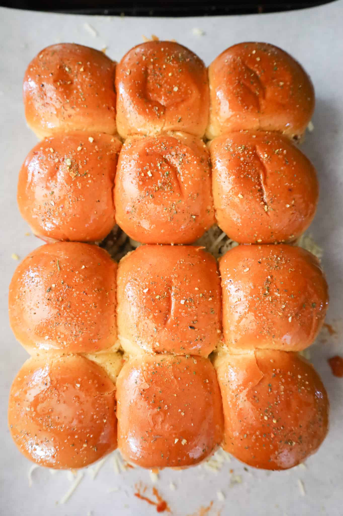 Italian seasoning sprinkled on top of meatball slider buns