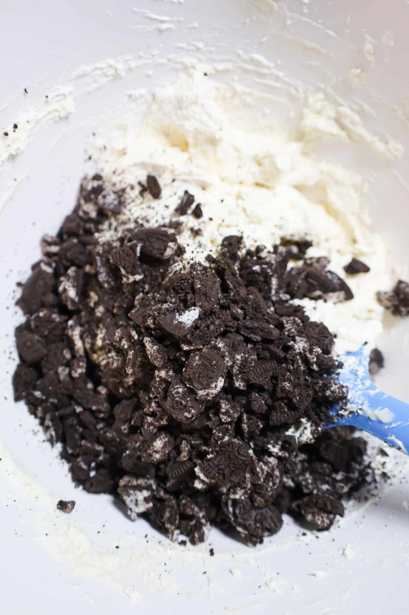 crumbled Oreos added to a bowl with cream cheese and cool whip mixture