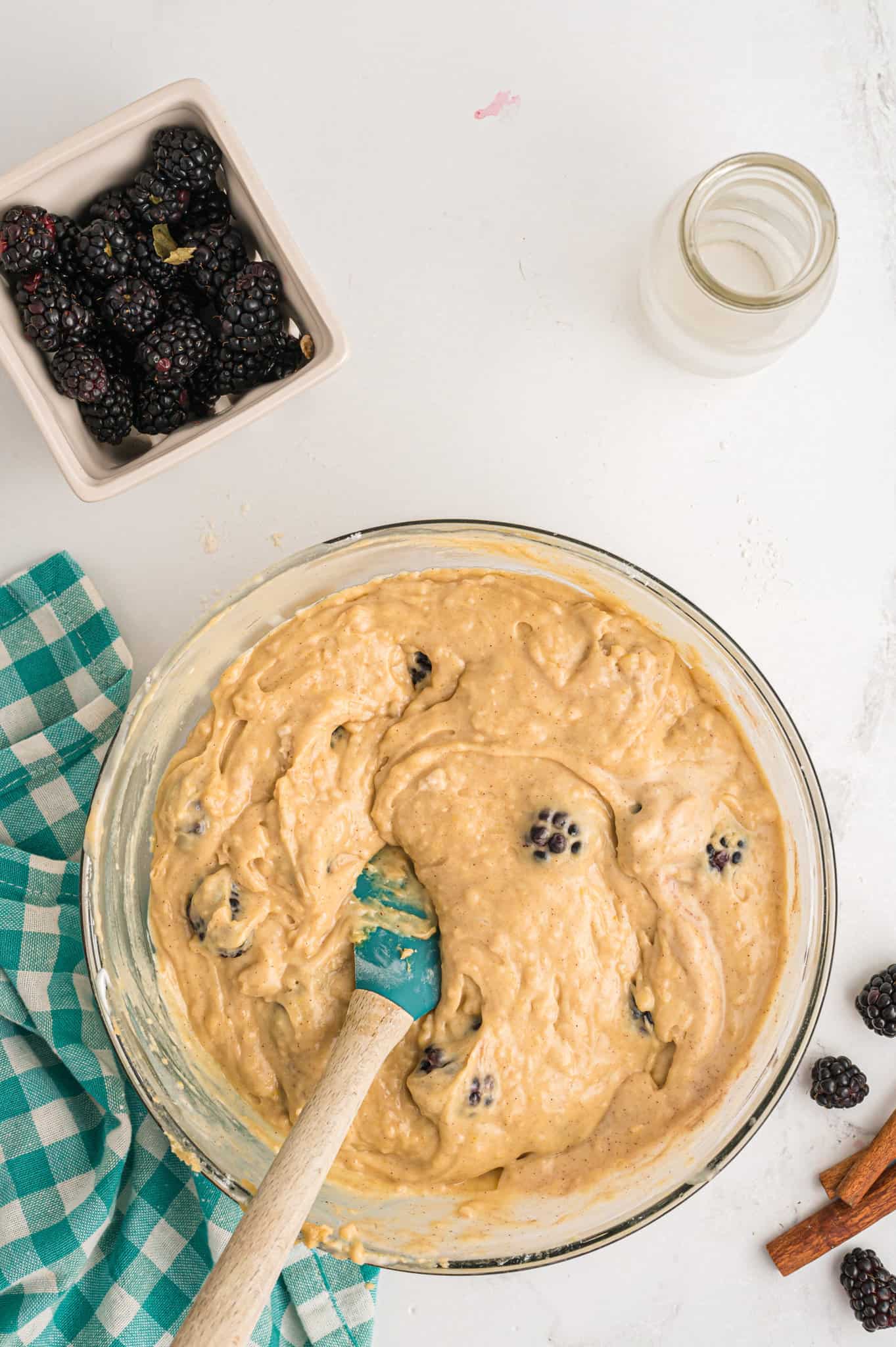 fresh blackberries stirred into muffin batter in a mixing bowl