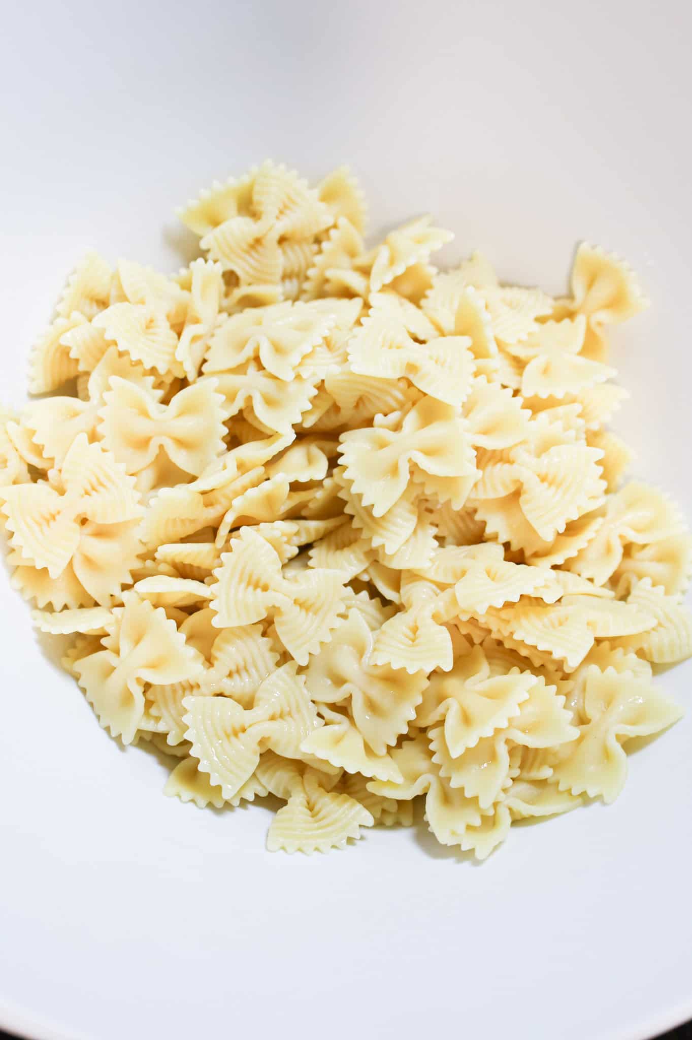 cooked bowtie pasta noodles in a mixing bowl
