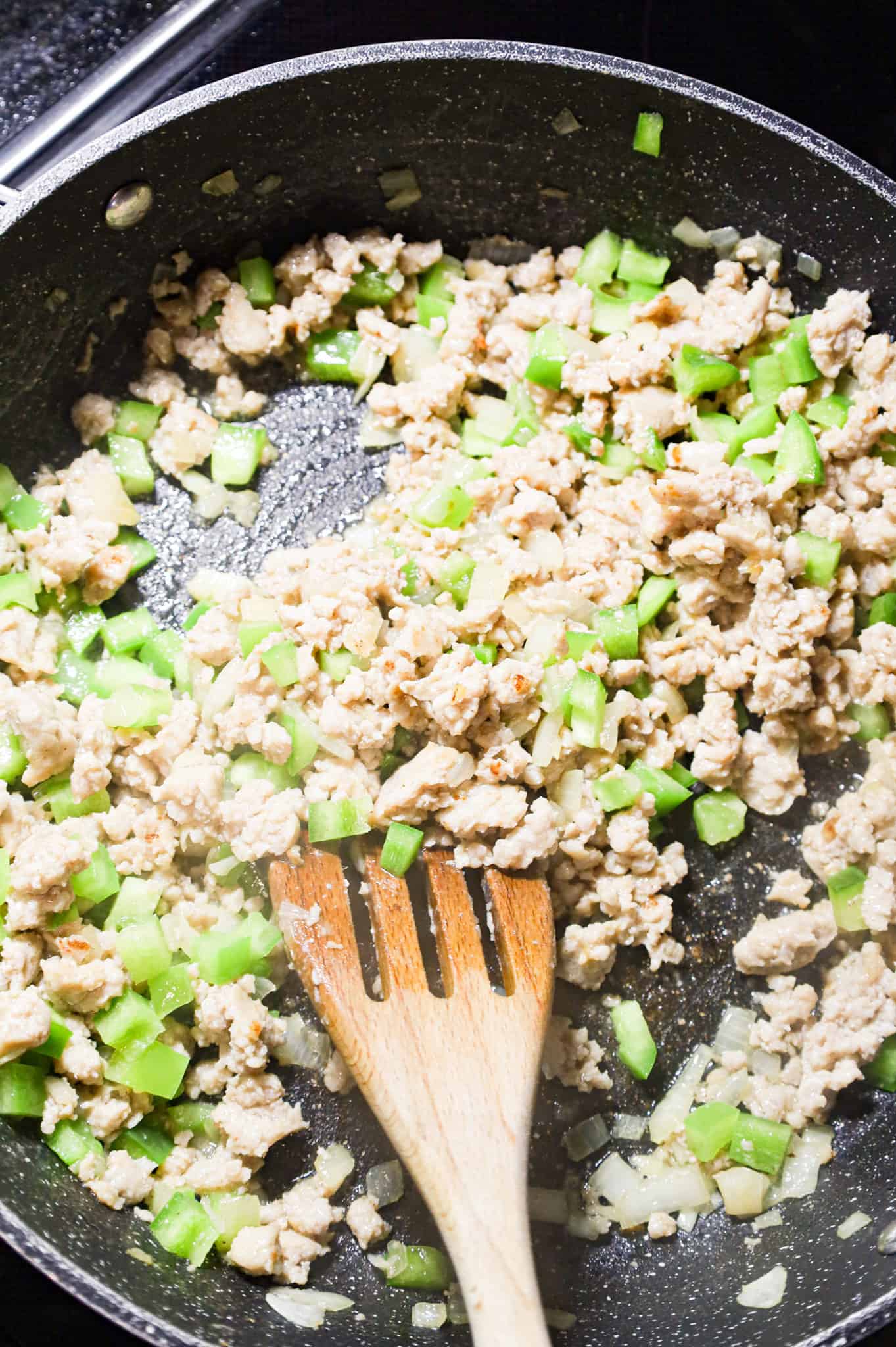 browned sausage and diced green peppers in a skillet