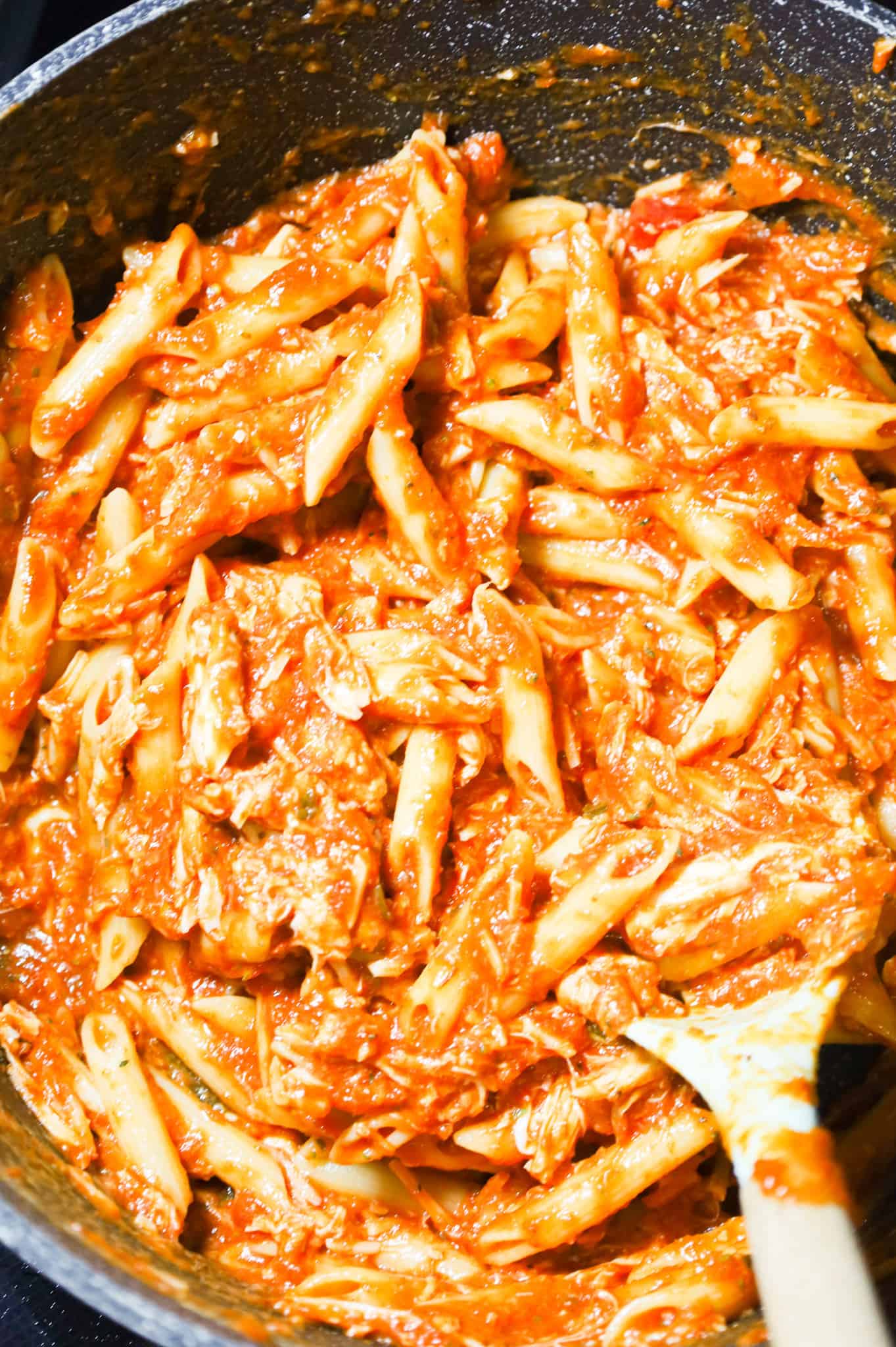 chicken marinara and penne being stirred in a large pot