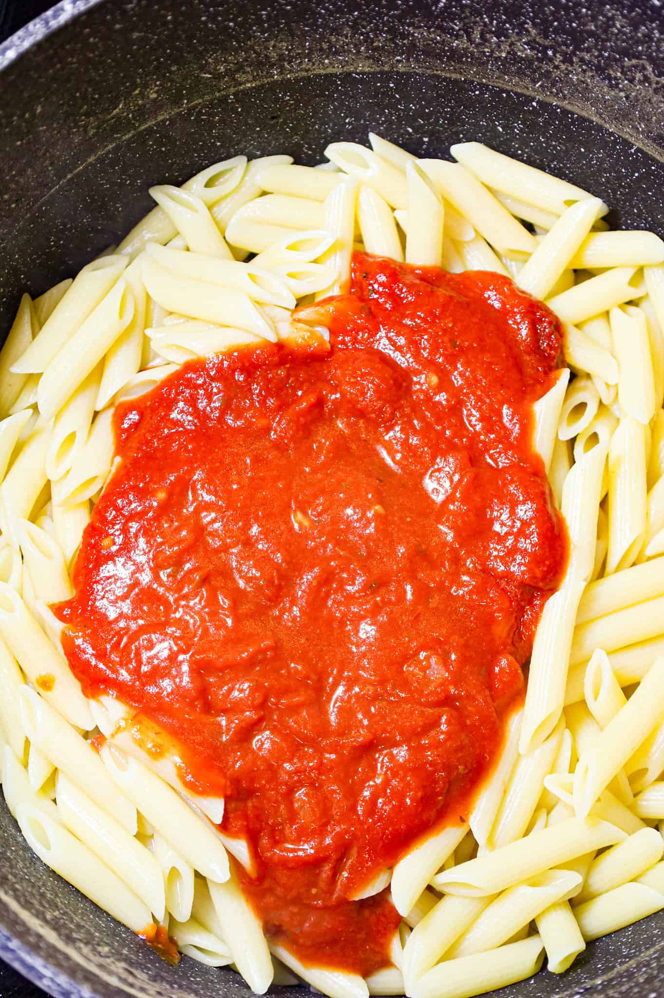 marinara sauce on top of cooked penne in a pot