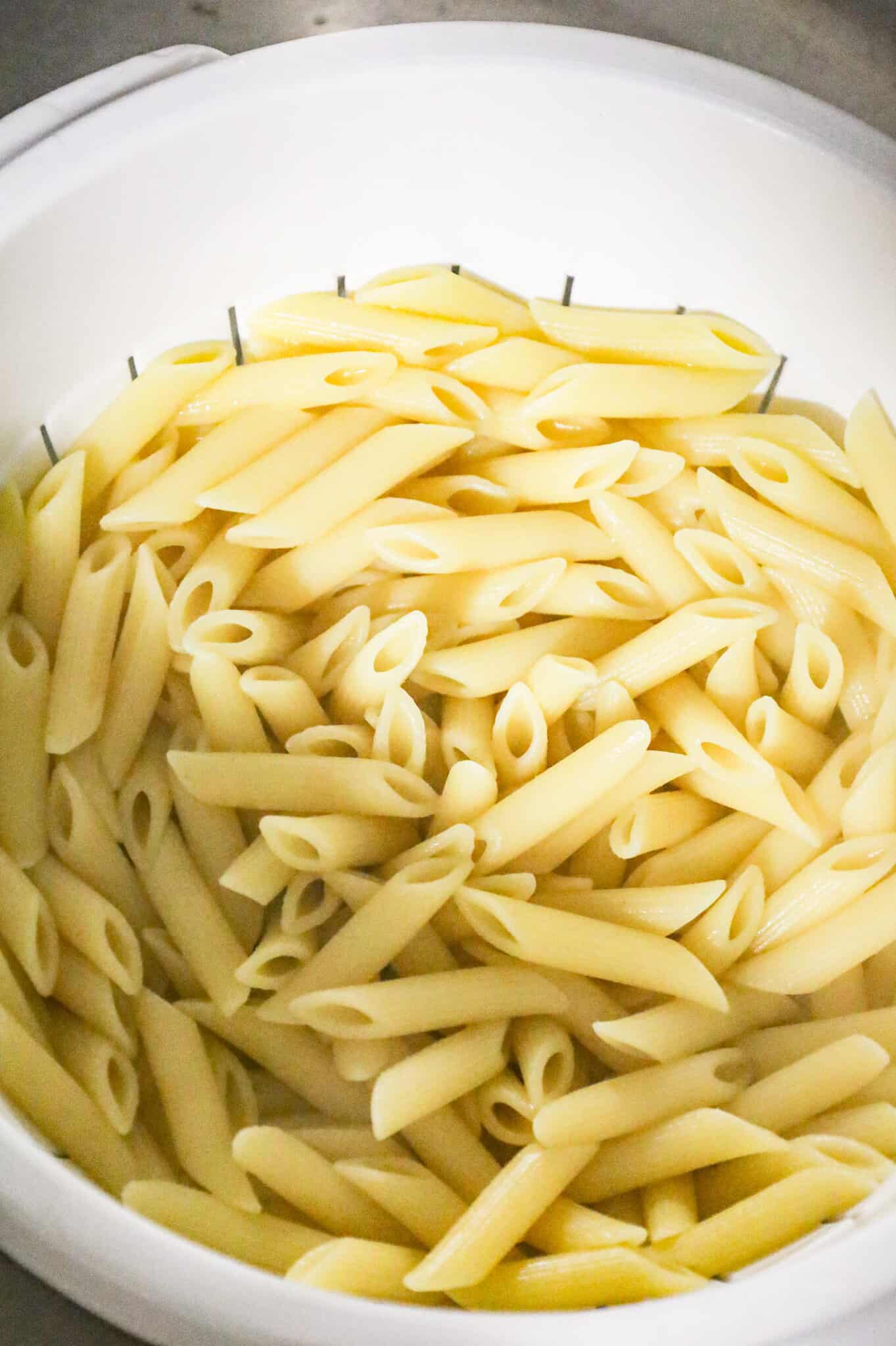 cooked penne pasta in a colander