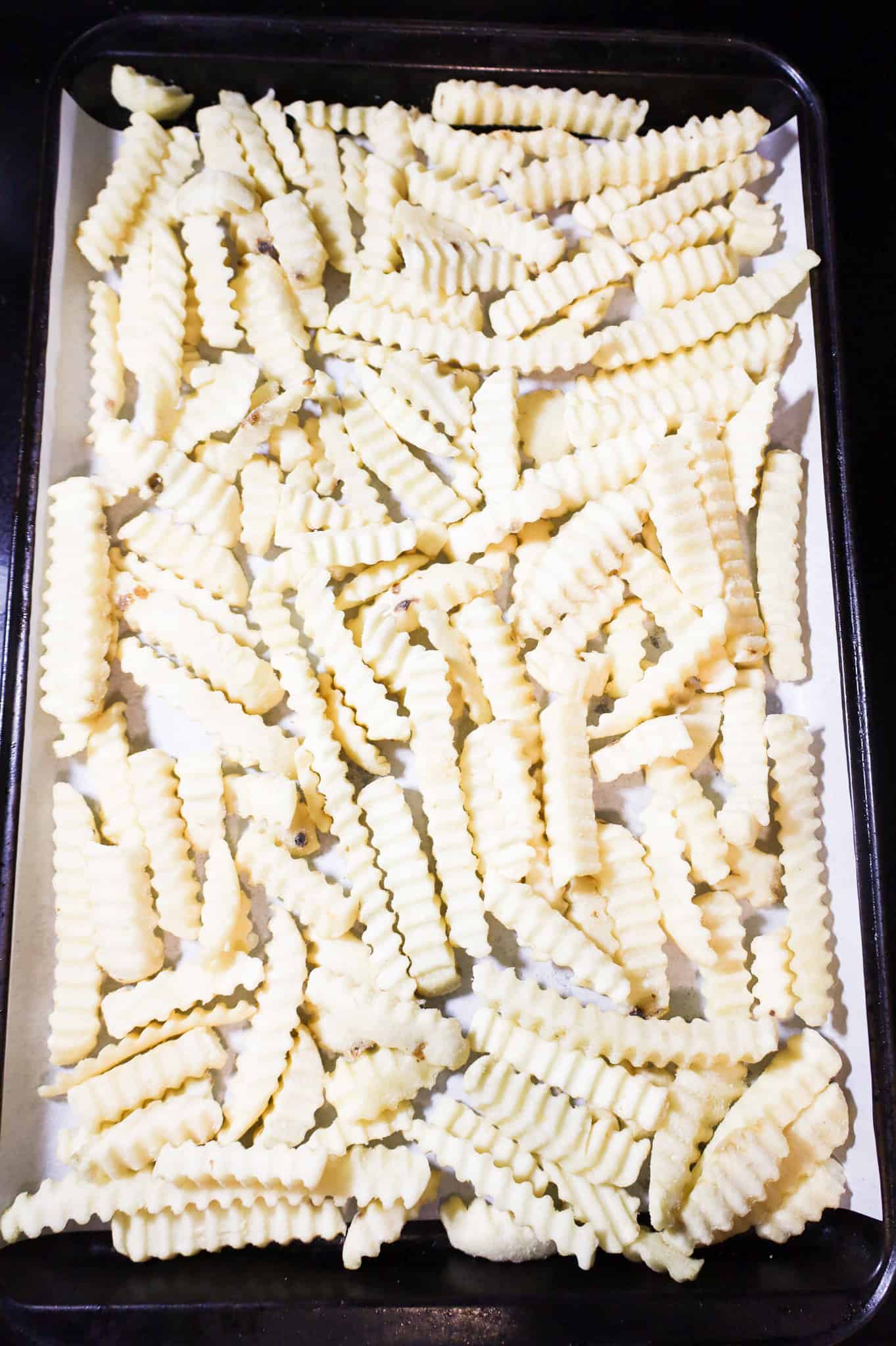 frozen crinkle cut fries on a parchment lined baking sheet