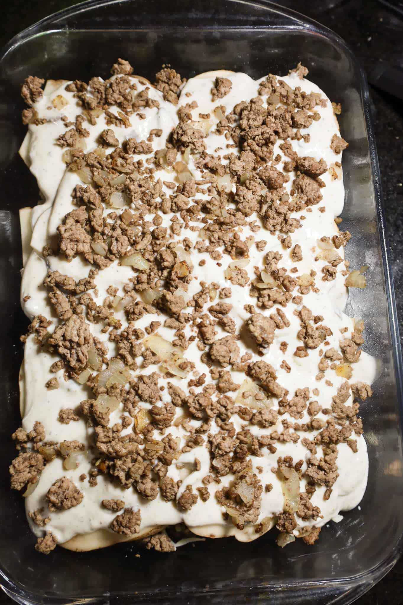 crumbled ground beef on top of cream of mushroom soup mixture and sliced potatoes in a baking dish