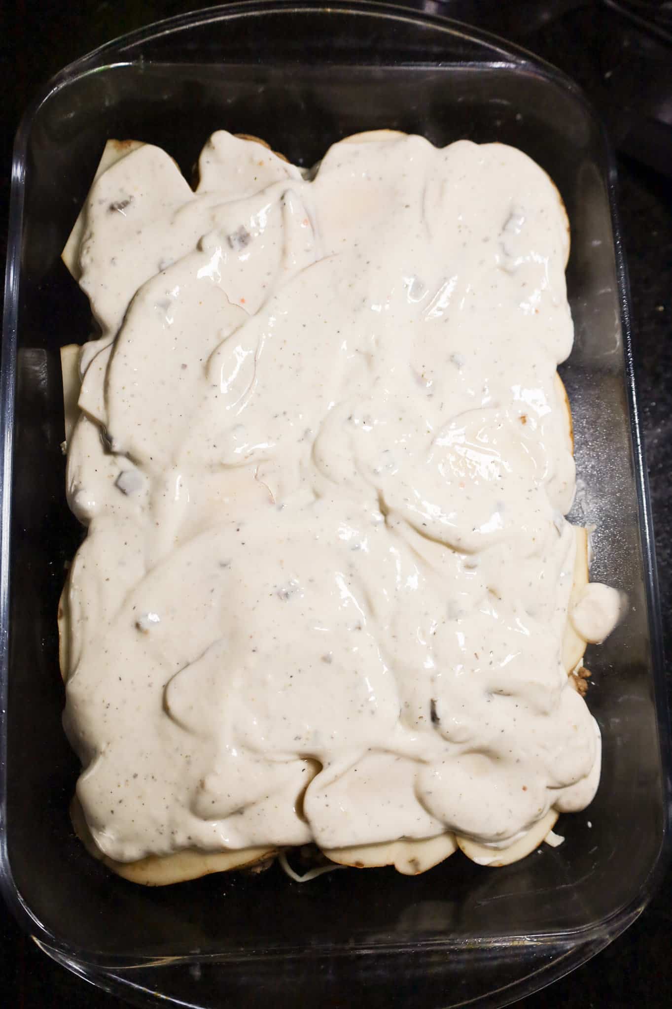 cream of mushroom soup mixture spread on potato slices in a baking dish