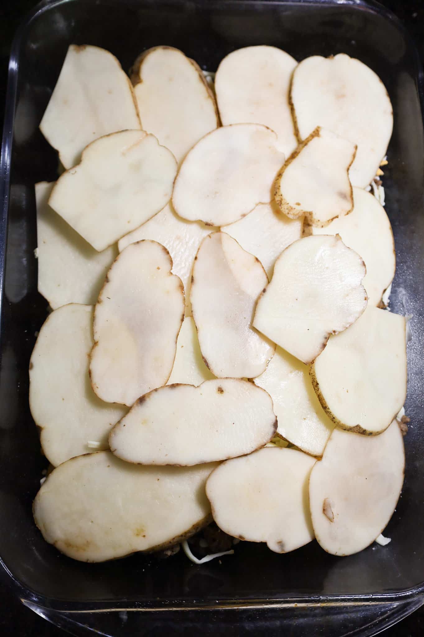 sliced potatoes in the bottom of a 9 x 13 inch baking dish