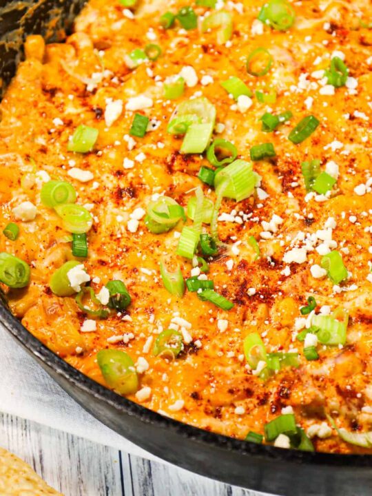 Mexican Street Corn Dip is a tasty hot party dip recipe loaded with corn, cream cheese, sour cream, chili powder, crumbled feta, red onions and shredded cheese.