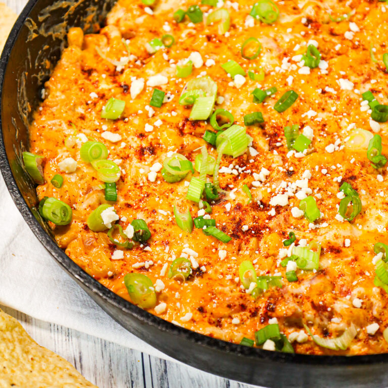 Mexican Street Corn Dip is a tasty hot party dip recipe loaded with corn, cream cheese, sour cream, chili powder, crumbled feta, red onions and shredded cheese.