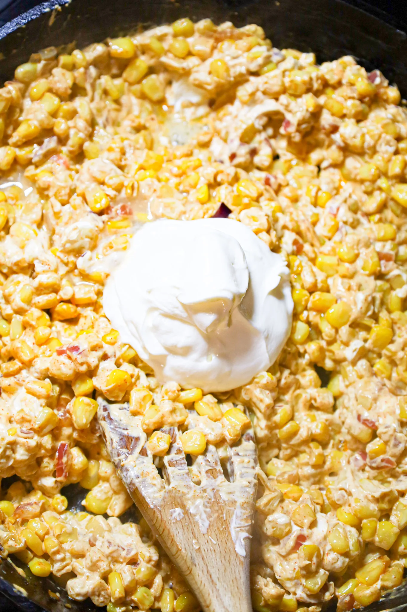 sour cream on top of cream cheese and corn mixture in a skillet