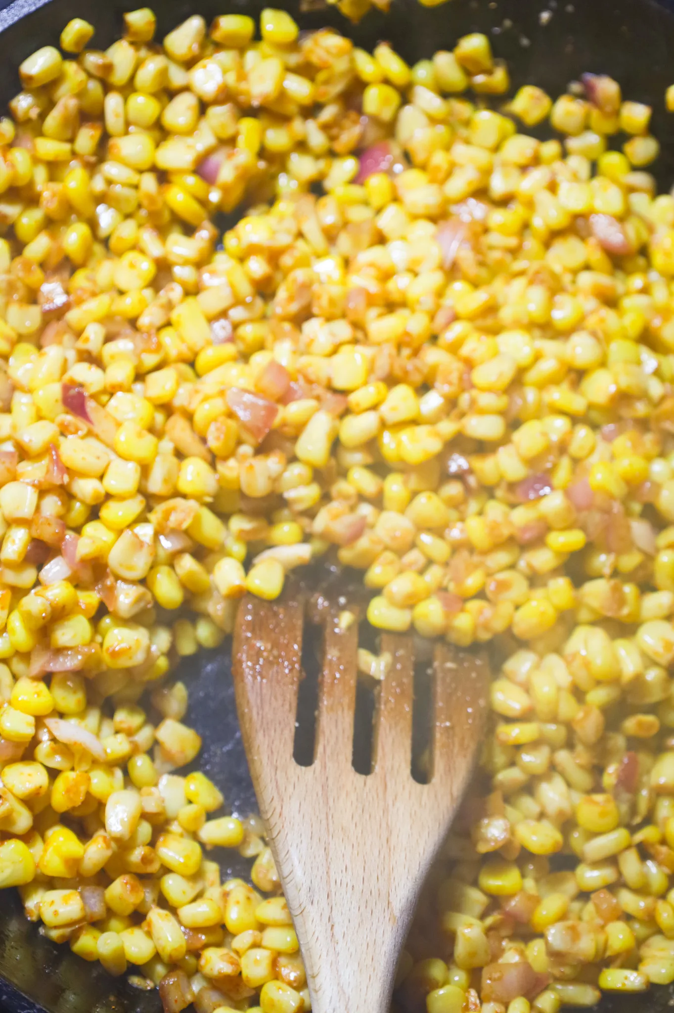 stirring together corn, diced red onions and chili powder in a skillet