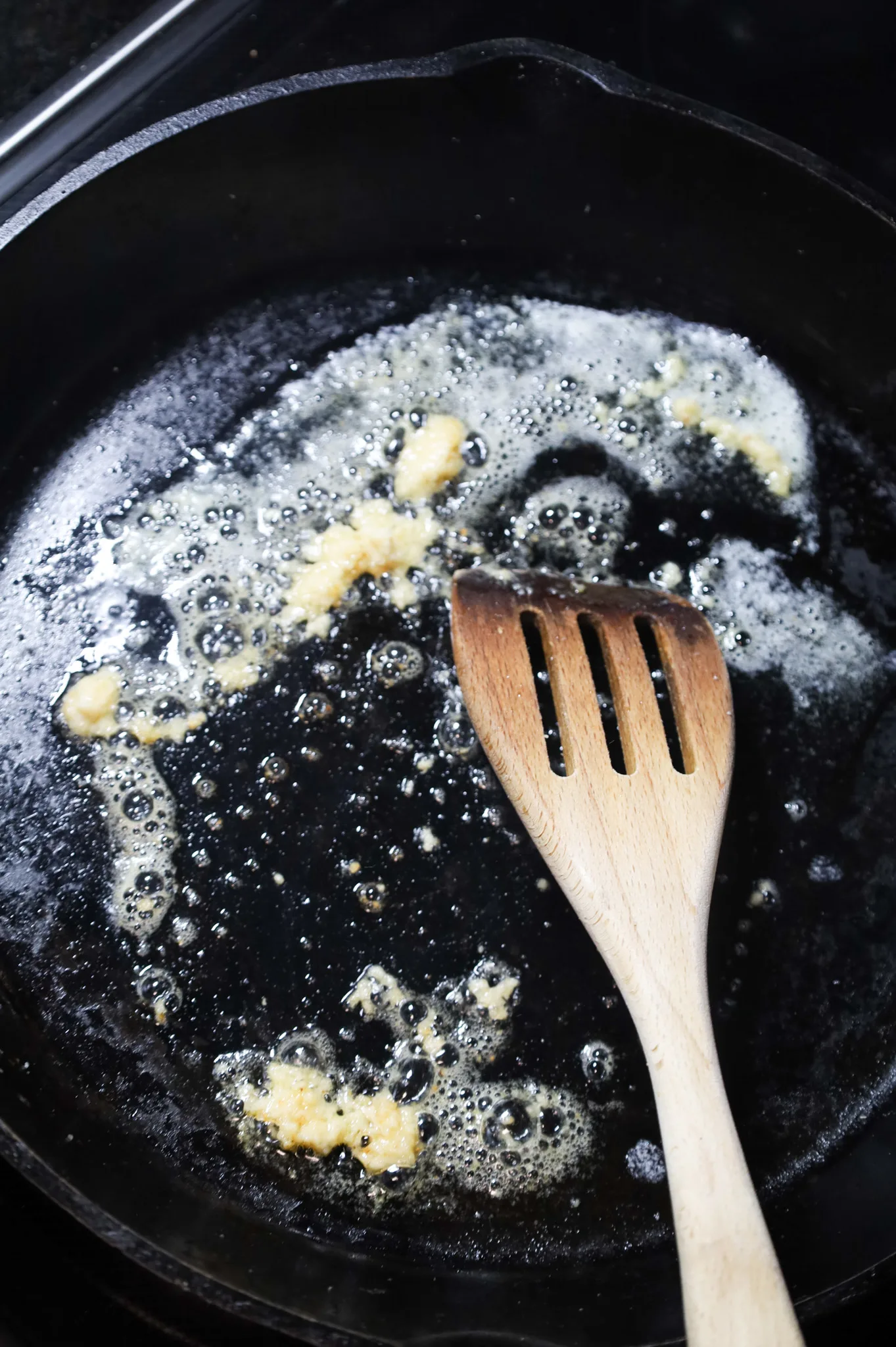 garlic puree and melted butter being stirred together in a cast iron skillet