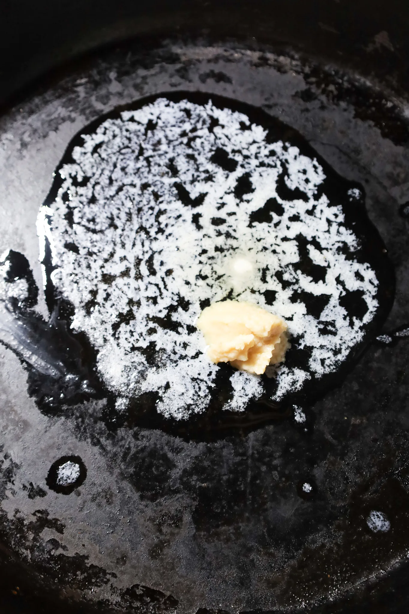 garlic puree added to a cast iron skillet with melted butter