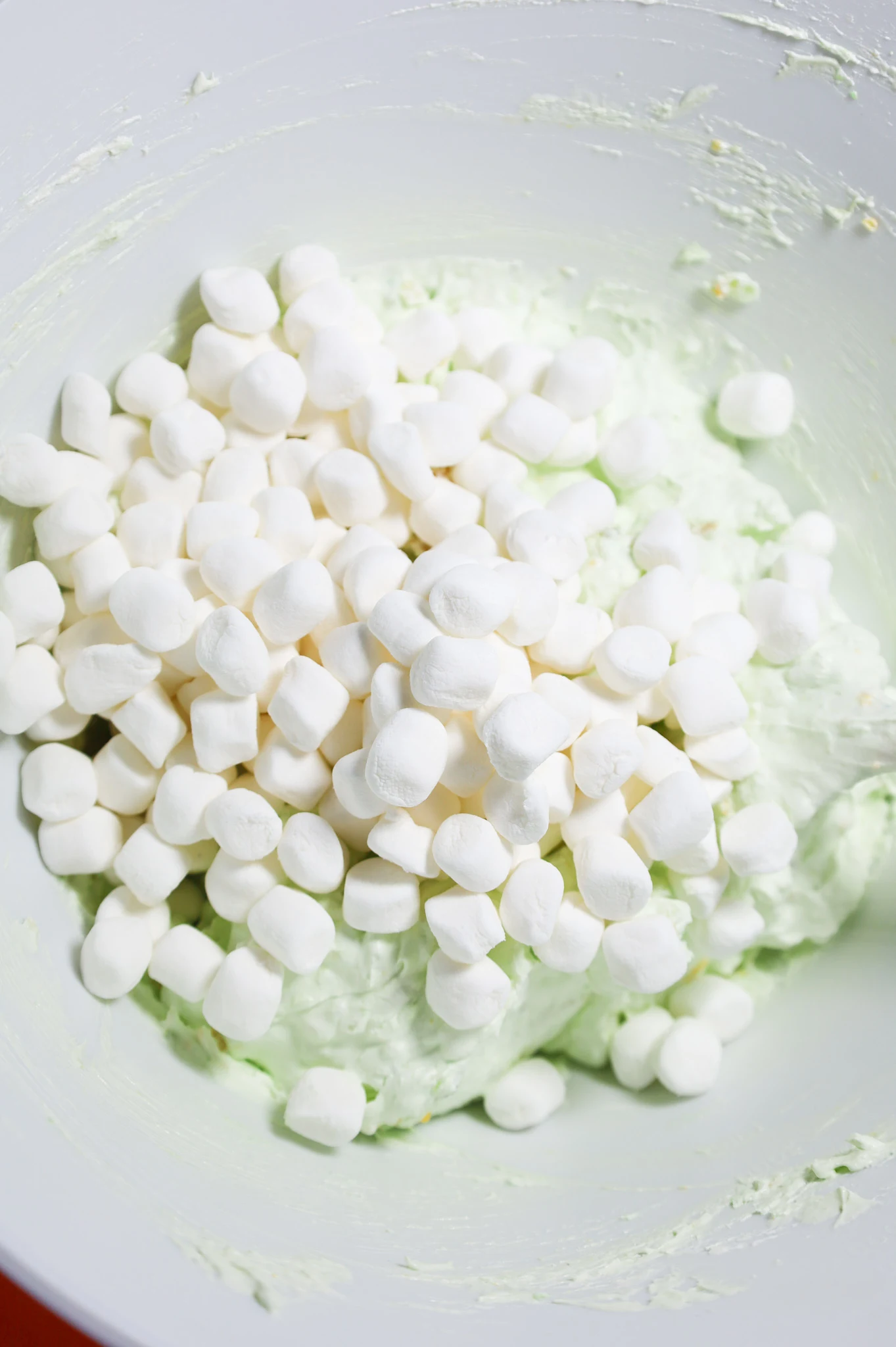 mini marshmallows on top of Cool Whip and pistachio pudding mixture in mixing bowl