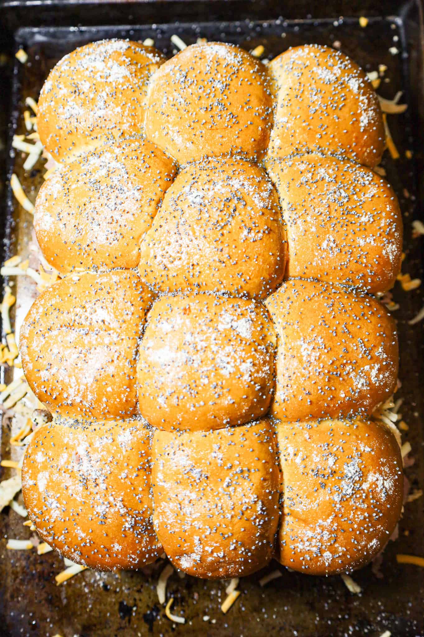 poppy seed, onion powder and garlic powder mixture sprinkled on slider buns on a baking sheet